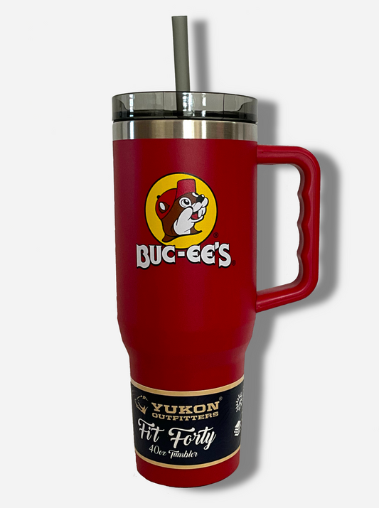 A picture of a tall, red, sorta skinny tumbler, with a big picture of Buc-ee The Beaver on it.  The surface is smooth and red, as it is red paint covering stainless steel.  The handle, top, and straw are plastic.  The top of the mug is lined with a stainless steel band.  A paper wrapper around the bottom reads: Yukon Outfitters.  Fit Forty 40 oz Tumbler.