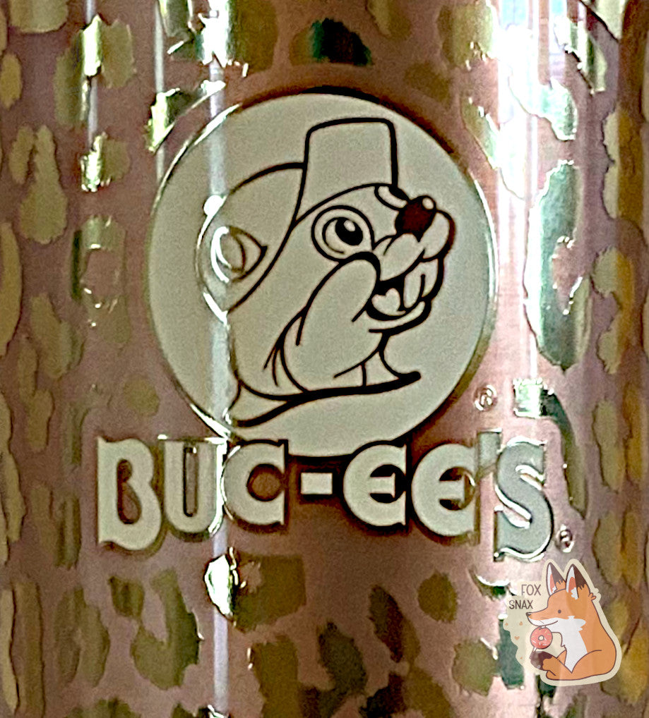 A closeup of the front of the Gold Leopard Print  tumbler, with a big picture of Buc-ee The Beaver on it.  The surface is a leopard print, as it is gold paint covering stainless steel. 