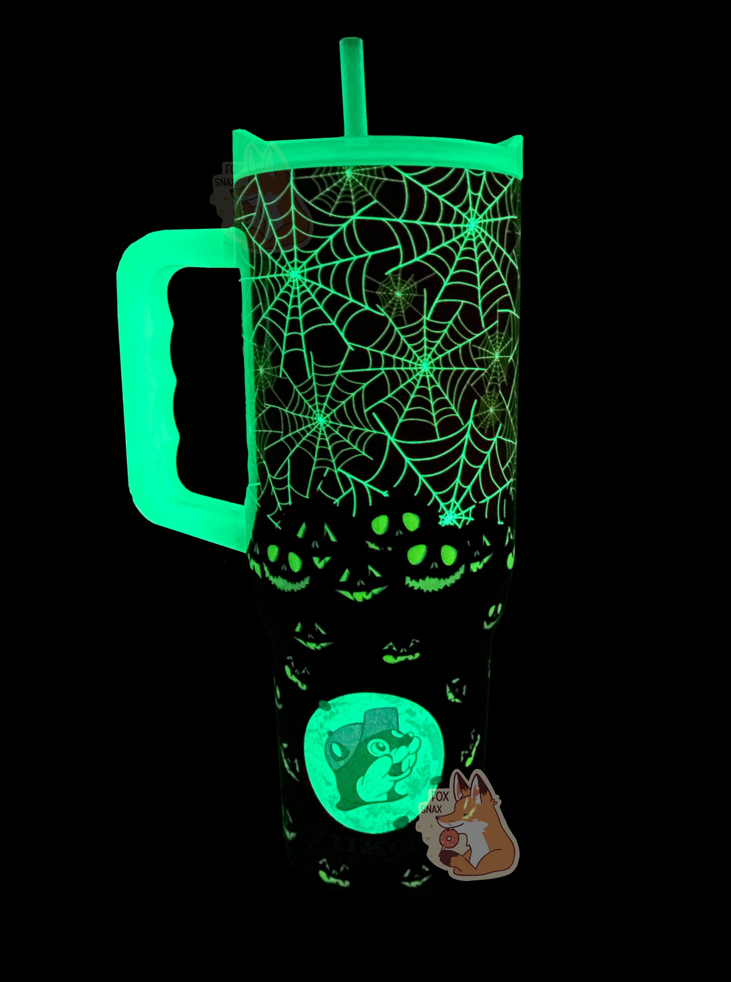 A picture of the back of a tall, dark sorta skinny tumbler.  The spiderwebs on the top of the tumbler are glowing green, as are the jack-o-lanterns on the bottom.  The straw, lid, and handle are also glowing green.  On the bottom of the tumbler is a glowing full moon with Buc-ee the Beaver's head in the middle.