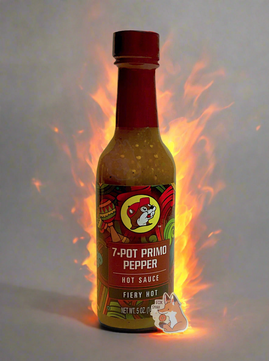 A picture of a small, tall glass bottle of hot sauce.  The top of the bottle is sealed with a plastic top.  The front label of the bottle reads 7-POT PRIMO PEPPER HOT SAUCE, FIERY HOT.  The Buc-ee's logo can be seen on the front; the background is a fairly busy abstract artwork featuring a heart, two maracas, and various colorful swooshes.  The sauce inside is a yellow/tan color, with pepper seeds visible.  Painted flames behind the bottle can be seen in the background.