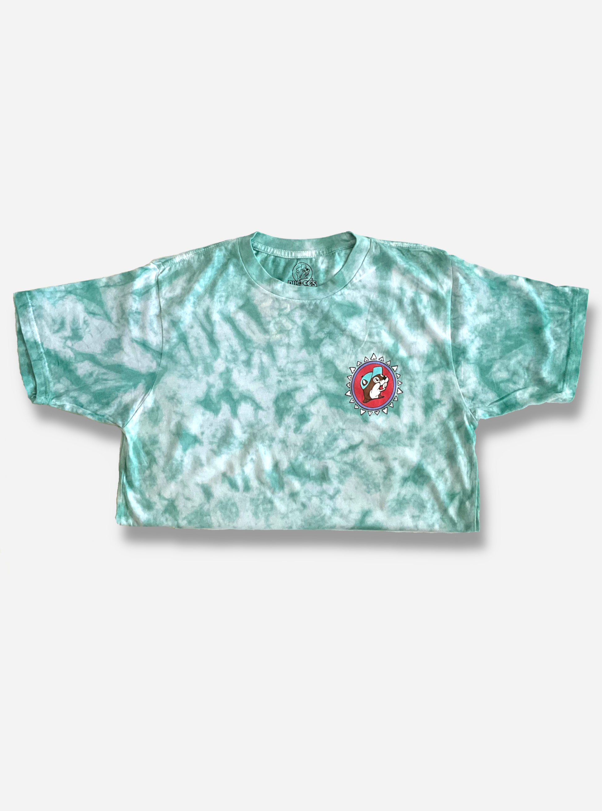 The front of a Buc-ee's Aztec t-shirt.  The background on the shirt is a blue/green tie dye color, against a white background.  On the front right of the shirt is the Buc-ee's logo, but the background is pink, not yellow.  Buc-ee's hat is a light blue, not red.  Finally, the logo is surrounded by a series of white triangles to give it an Aztec-like theme.