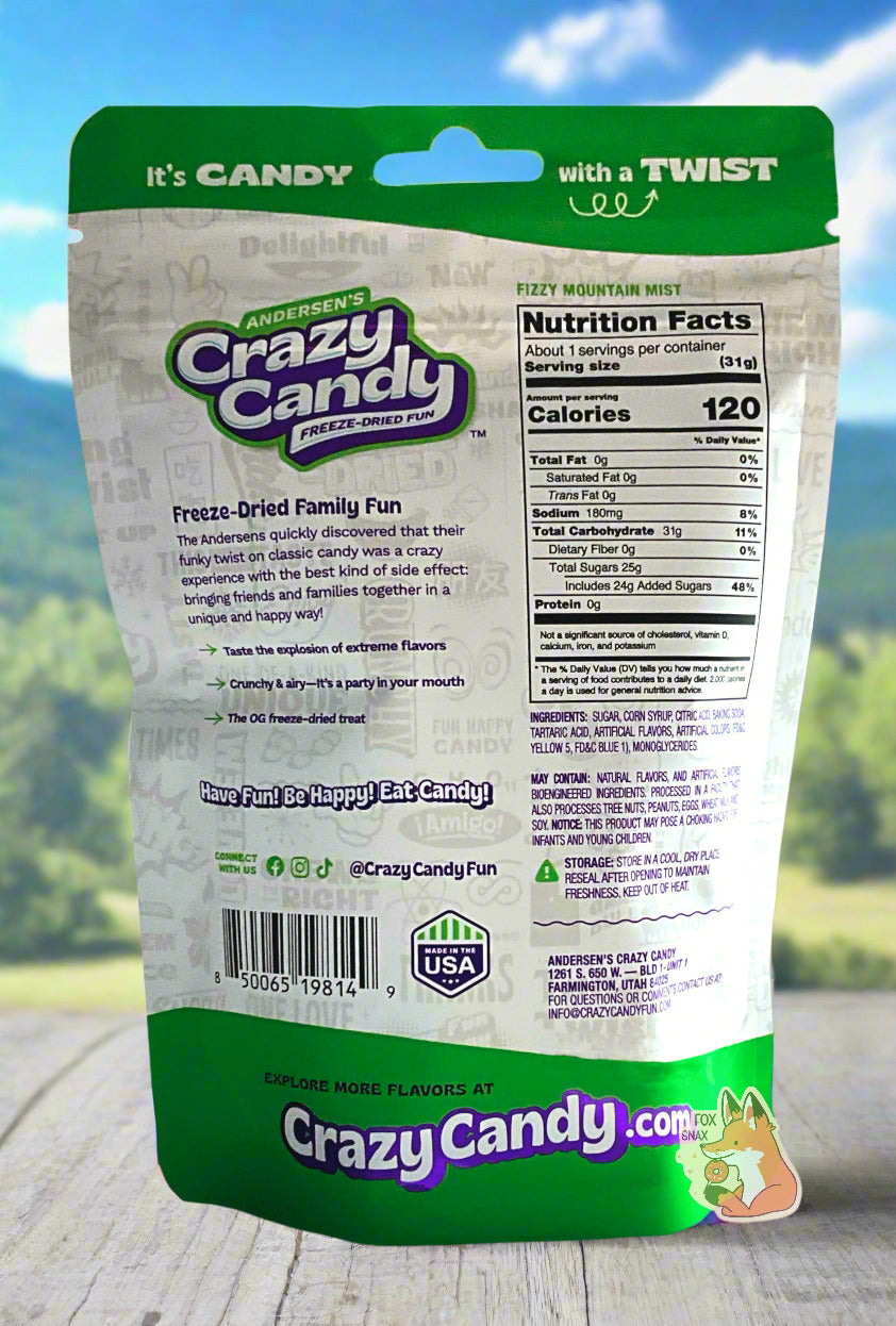 The back of a large bag of Andersen's Crazy Candy Fizzy Mountain Mist. The bag reads: Freeze Dried Family Fun.  The Andersens quickly discovered that their funky twist on classic candy was a crazy experience with the best kind of side effect: bringing friends and families together in a unique and happy way!   The bag sits on a white picnic table; behind the bag are distant mountains and pine trees against a pretty blue sky.