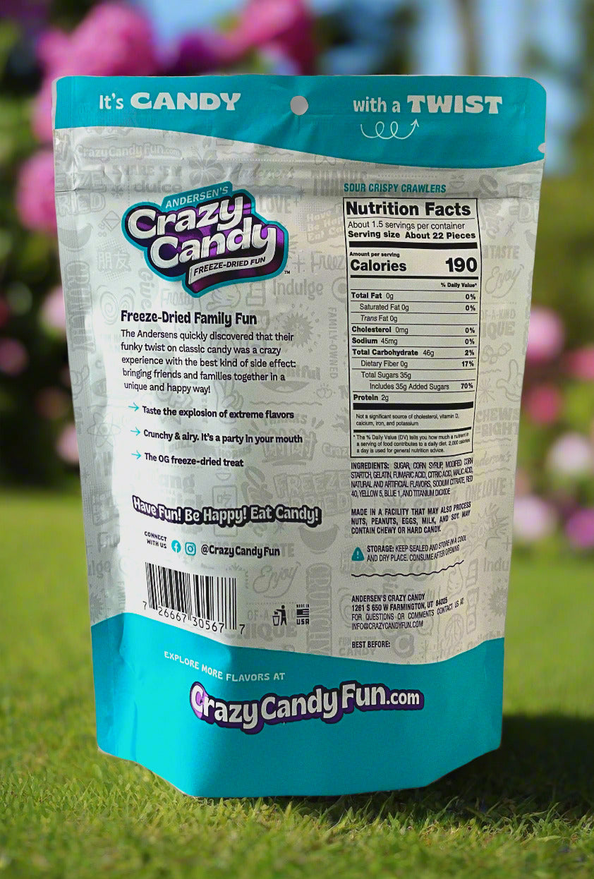 The back of a large bag of Andersen's Crazy Candy Sour Crispy Crawlers. The bag reads: Freeze Dried Family Fun.  The Andersens quickly discovered that their funky twist on classic candy was a crazy experience with the best kind of side effect: bringing friends and families together in a unique and happy way!  The background is of a pretty flower garden.