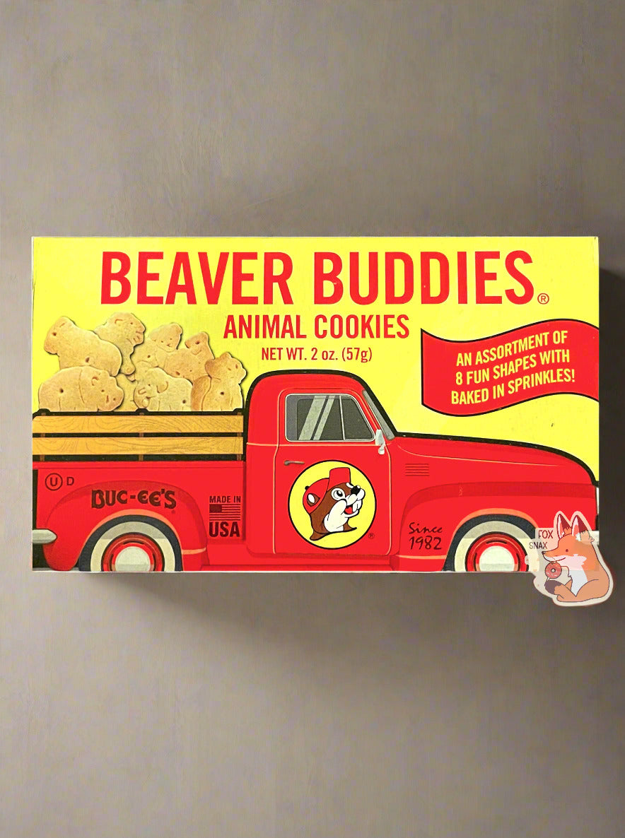 The front of a small rectangular cardboard package of Buc-ee's Beaver Buddies Animal Cookies.  The label has a picture of a red truck with the Buc-ee The Beaver logo on the door panel, and a series of animal cookies in the bed of the truck.  The text reads BEAVER BUDDIES ANIMAL COOKIES, NET WT 2 oz (57g).  AN ASSORTMENT OF 8 FUN SHAPES WITH BAKED IN SPRINKLES!  Made in the USA.  The background is of a clean kitchen counter.