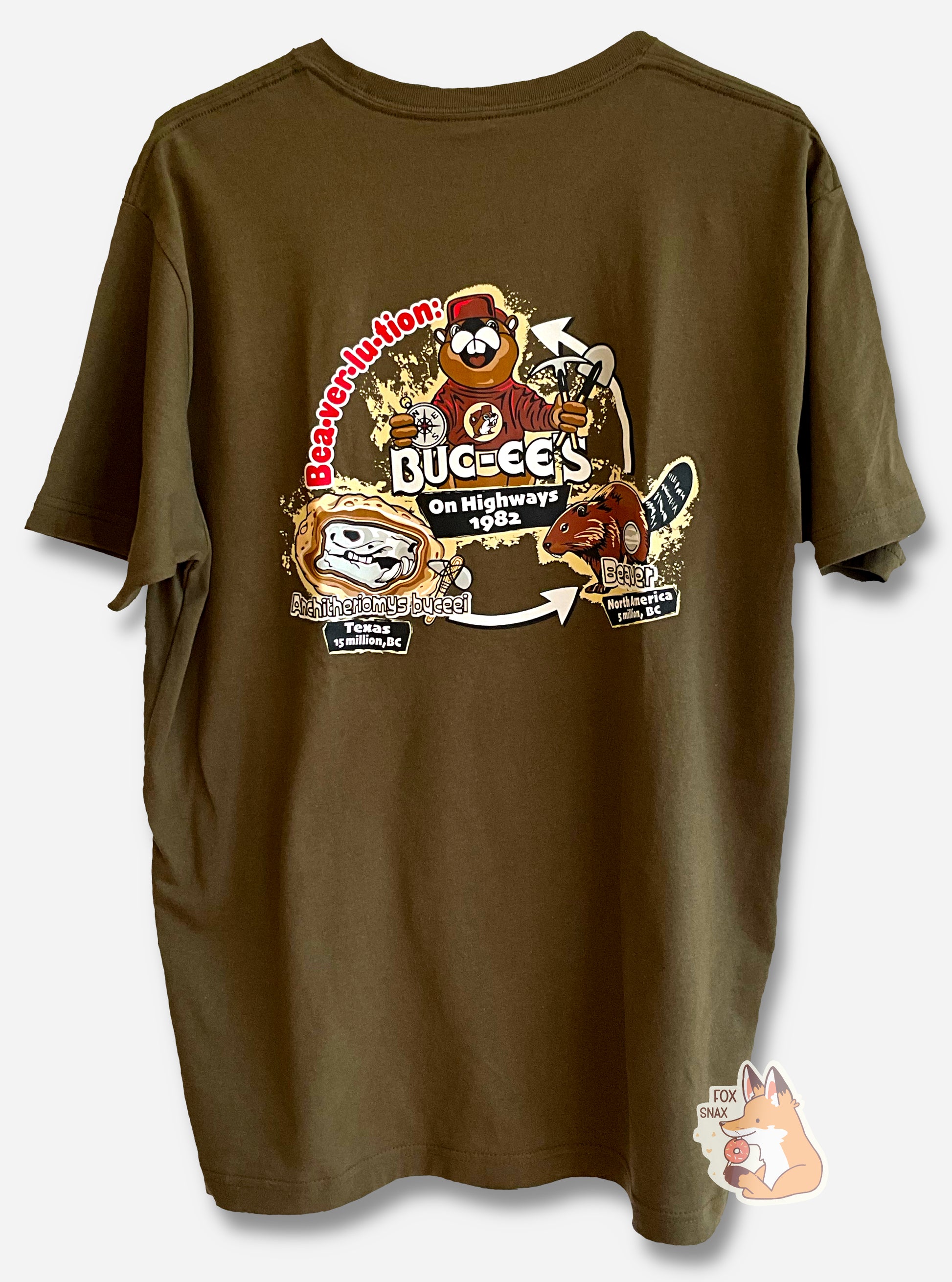 A picture of a tan t-shirt, with BEAVER-LU-ION in red text on the left.  In the middle are a triad of features, clockwise from lower left: a cartoon beaver skull that reads ANCHITHERIOMYS BUCEEI, TEXAS, 15 MILLION BC, then a picture of a realistic brown beaver that reads BEAVER, NORTH AMERICA, 5 MILLION BC, then a picture of an anthropomorphic Buc-ee the Beaver, holding a shovel and compass, that reads ON HIGHWAYS, 1982