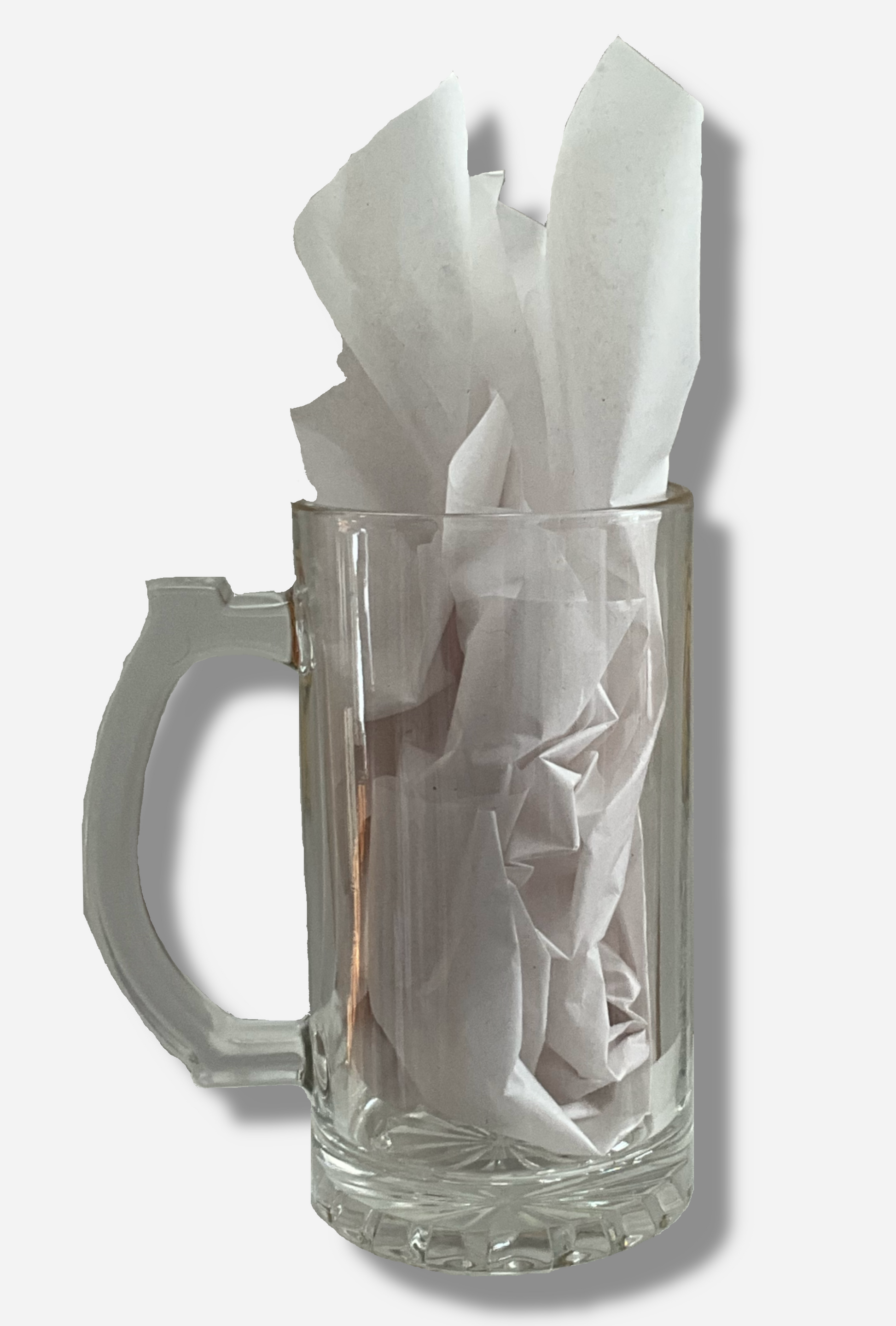 A picture of the back of clear beer mug. The glass is clear. The handle of the beer mug is also clear, and slightly blocky.  A ridged thumb area on the top can be seen.  The mug is filled with a white tissue paper to better illustrate what it looks like with material in it.