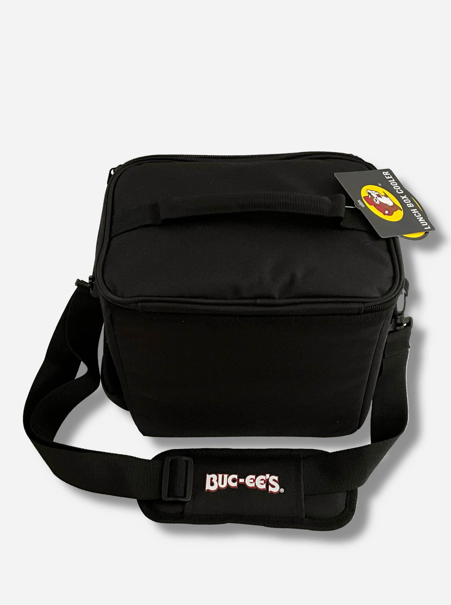 A picture of a the back of a lunch box cooler.  The outer surface is made of black polyester, and has large black strap on it that reads BUC-EE'S.  The top of the lunch box has a black fabric handle.