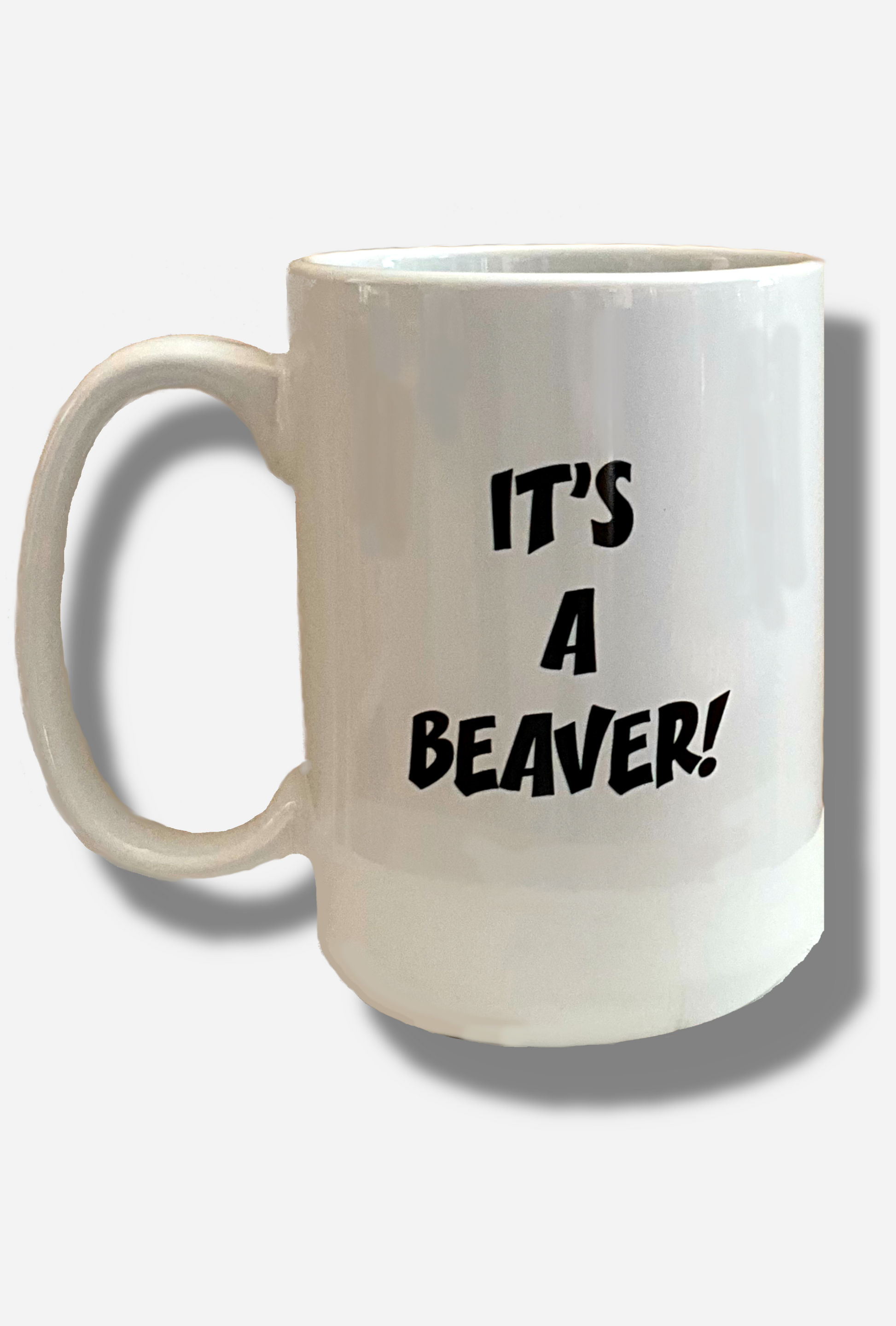 A picture of the back of a white ceramic coffee mug, with a white handle.  The middle of the mug reads IT'S A BEAVER! in a jolly font.