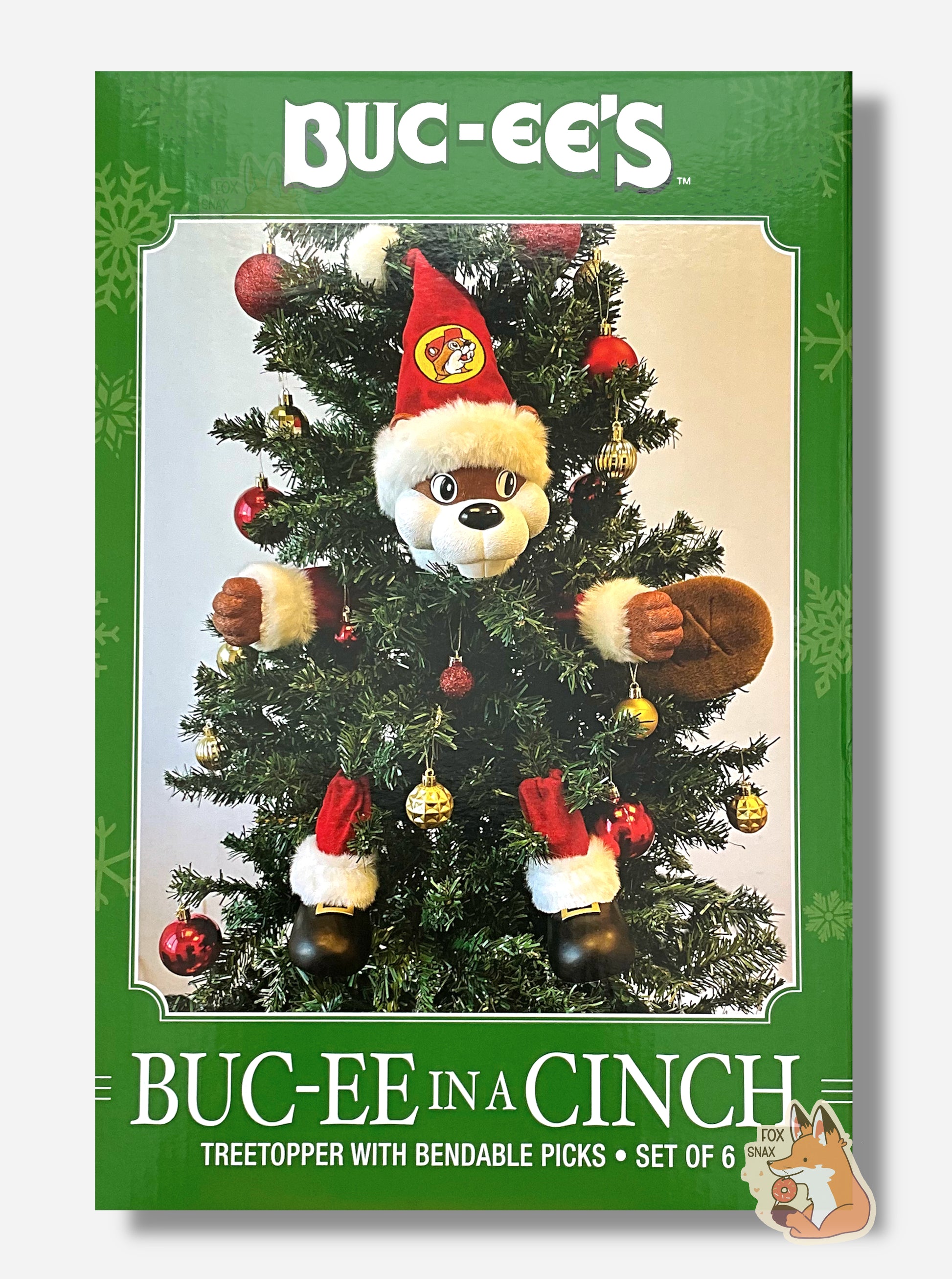 A picture of a large green rectangular box that reads BUC-EE'S BUC-EE IN A CINCH, Treetopper with bendable picks, set of 6, in white text.  In the center of the box is a Christmas tree, decorated with ornaments.  Going clockwise from top middle are: Buc-ee The Beaver's head, wearing a red pointed cap with a Buc-ee's logo, Buc-ee's left hand, Buc-ee's tail, Buc-ee's left leg, Buc-ee's right leg, then Buc-ee's right hand.  Buc-ee's arms and legs are suited with a red Santa-like outfit; his shoes are black.