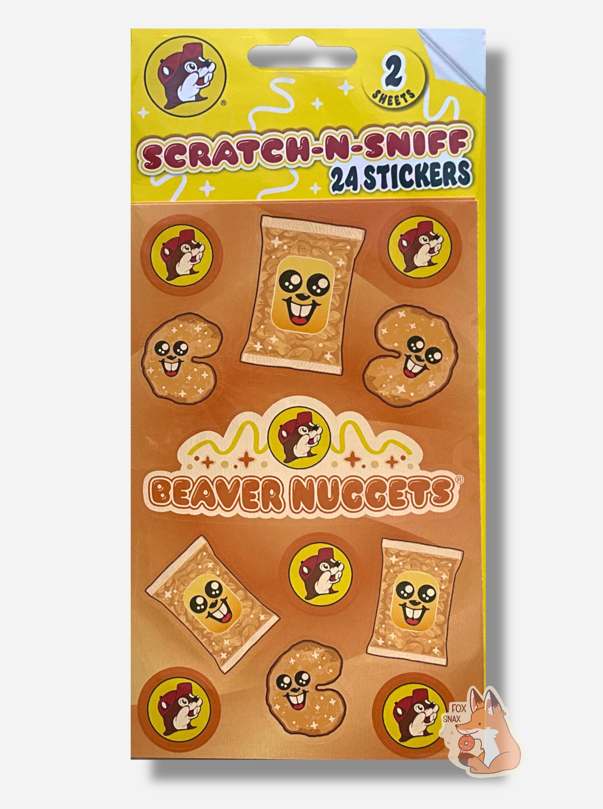 A rectangular package of Buc-ee's Scratch-N-Sniff Beaver Nuggets stickers.  The stickers on the package are the Buc-ee's logo - a brown-furred beaver with a massive overbite, a singular beaver nugget with a beaver grin on its body, package of beaver nuggets with a similar beaver grin (it's all a bit surreal), and in the middle, a Buc-ee's logo with the words BEAVER NUGGETS.  The top of the package reads 2 SHEETS, then SCRATCH-N-SNIFF, 24 STICKERS
