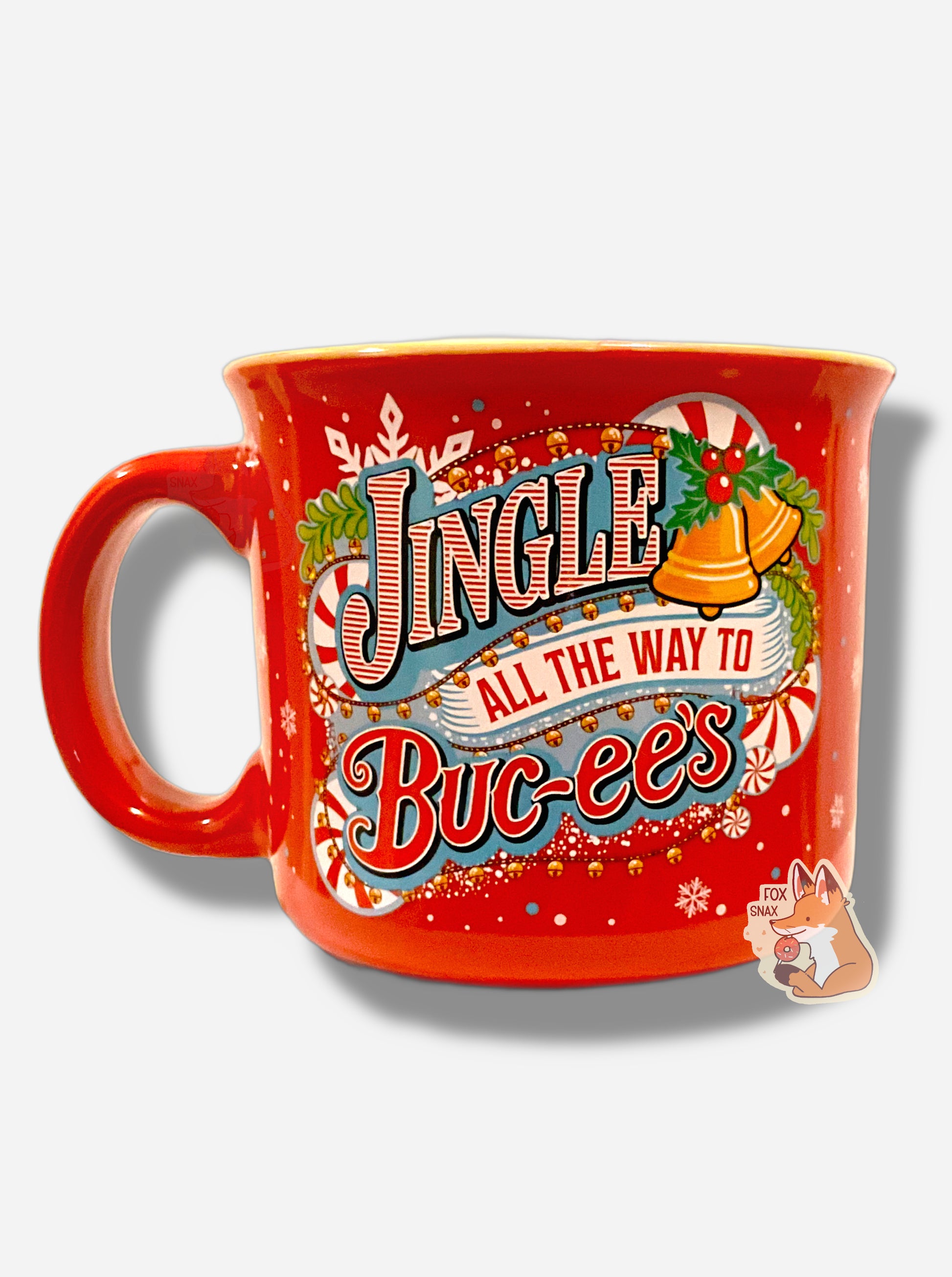 A festive, red ceramic mug, covered in  white snowflakes and red/white peppermints.  The mug is decorated with the words JINGLE ALL THE WAYS TO BUC-EE'S.  These words are framed with yellow jingle bells, holly leaves and berries, peppermints, and snowflakes.  The handle of the mug is red.