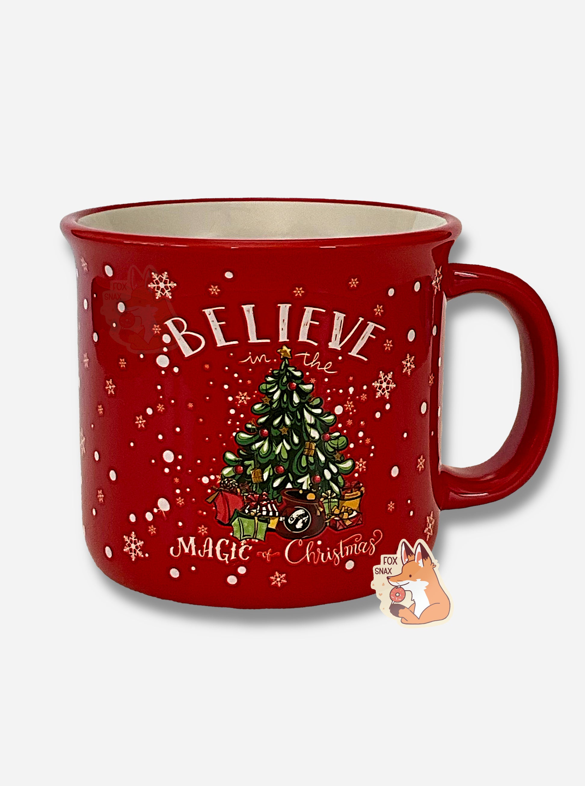 A festive, red ceramic mug, covered in ornate white snowflakes.  In the center is a large Christmas tree, decorated with snow, red globes, and a yellow star at the top.  Underneath the tree are many presents, including one with the Buc-ee's logo.  Above and below the tree read the words: BELIEVE IN THE MAGIC OF CHRISTMAS.  The inside of the mug is white.  The handle of the mug is red.