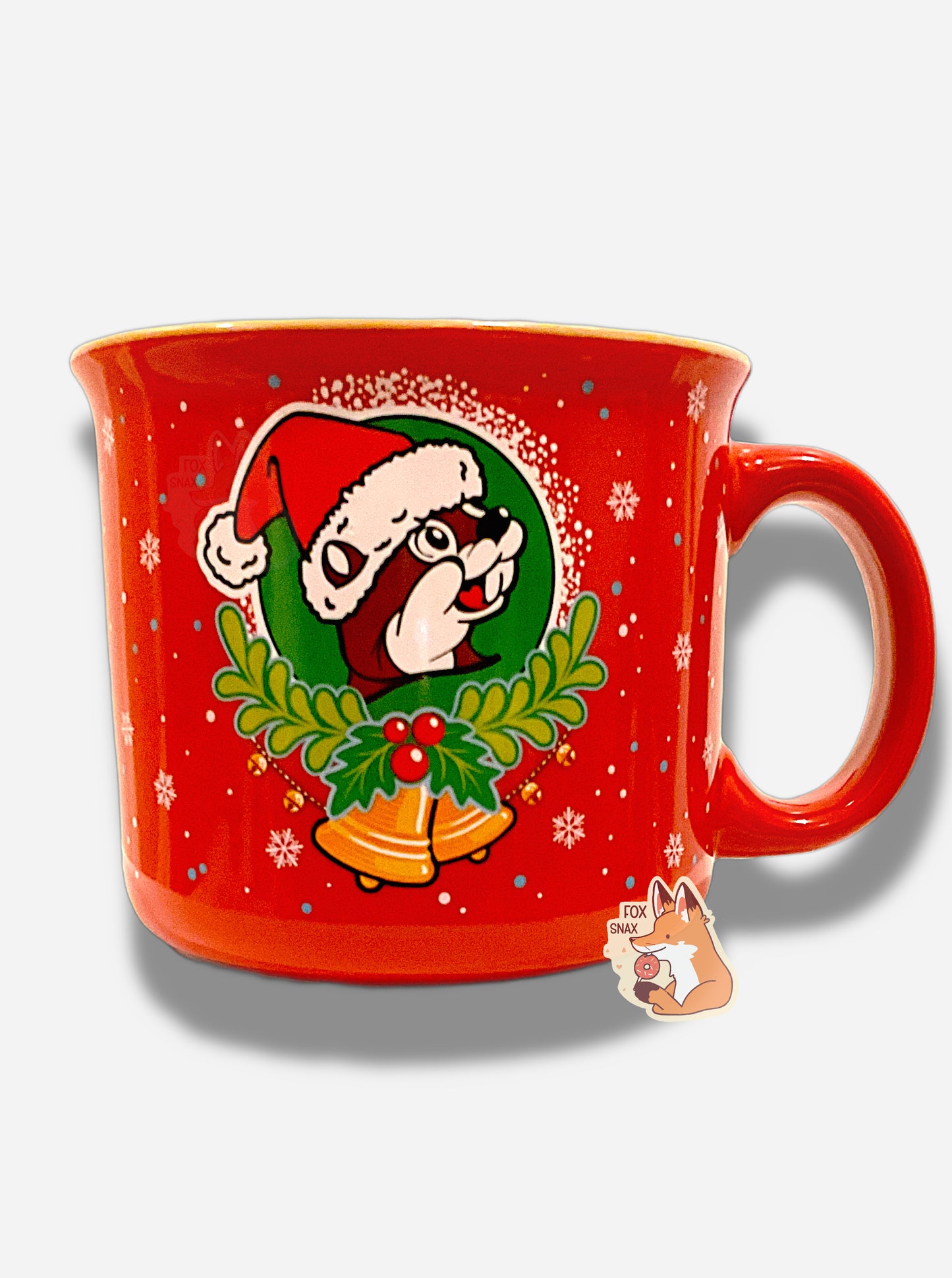 The front of a festive, red ceramic mug, covered in small white snowflakes.  In the center is a Buc-ee's logo, but altered so the background is dark green instead of yellow, and Buc-ee is wearing a Santa hat (red with a white pom) instead of his usual red ballcap.  The logo is surrounded with a white snow 'halo', the bottom of which has holly and two yellow Christmas bells. The handle of the mug is red.