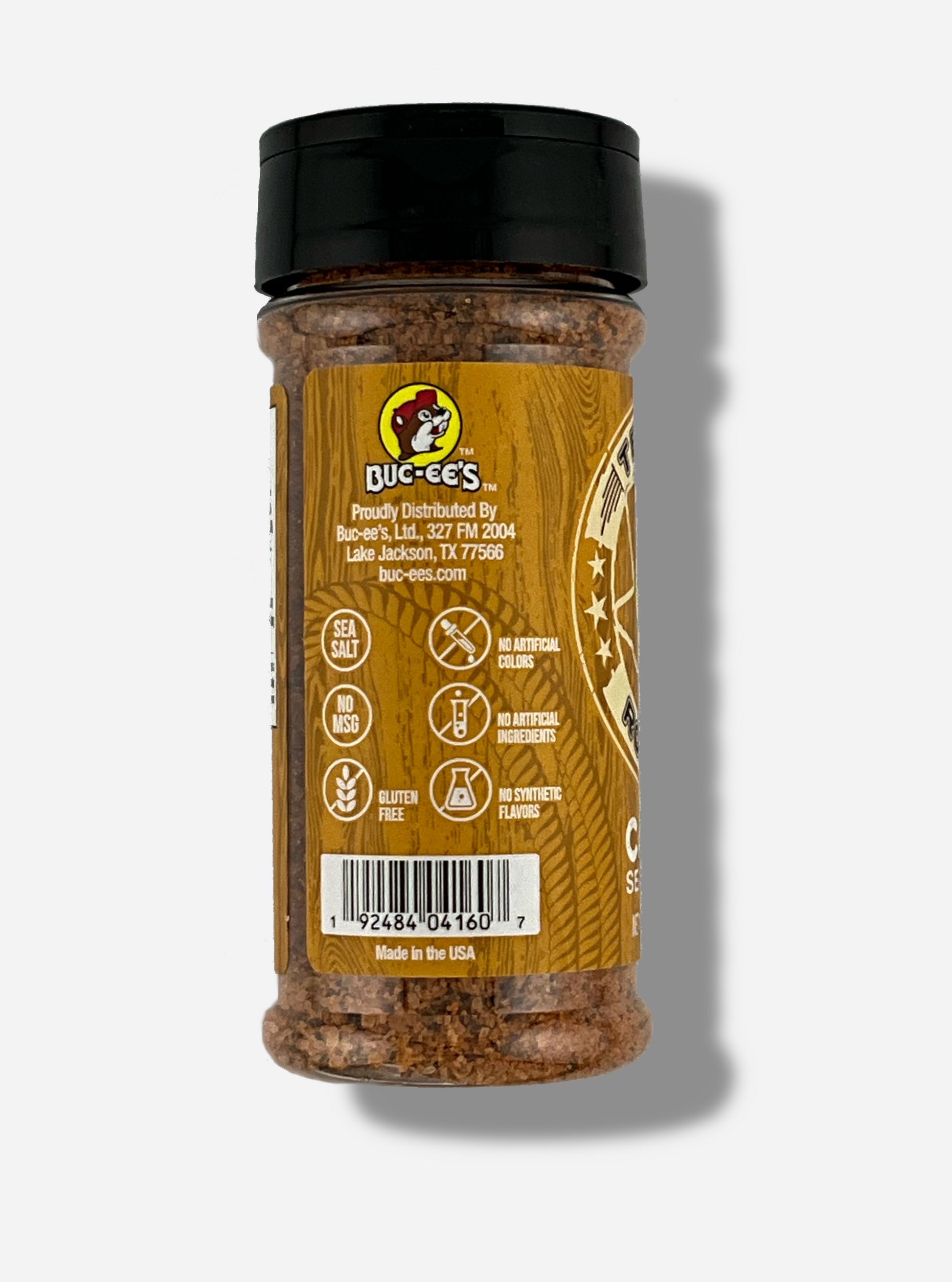 A picture of the side of a container of Texas Round Up Cajun Seasoning. The container has a black plastic flip lid, and a clear plastic body.  The spices inside appear orange and black.  The tan label reads SEA SALT, NO MSG, GLUTEN FREE, NO ARTIFICIAL COLORS, NO ARTIFICIAL INGREDIENTS, NO SYNTHETIC FLAVORS.  Beneath that, MADE IN THE USA.