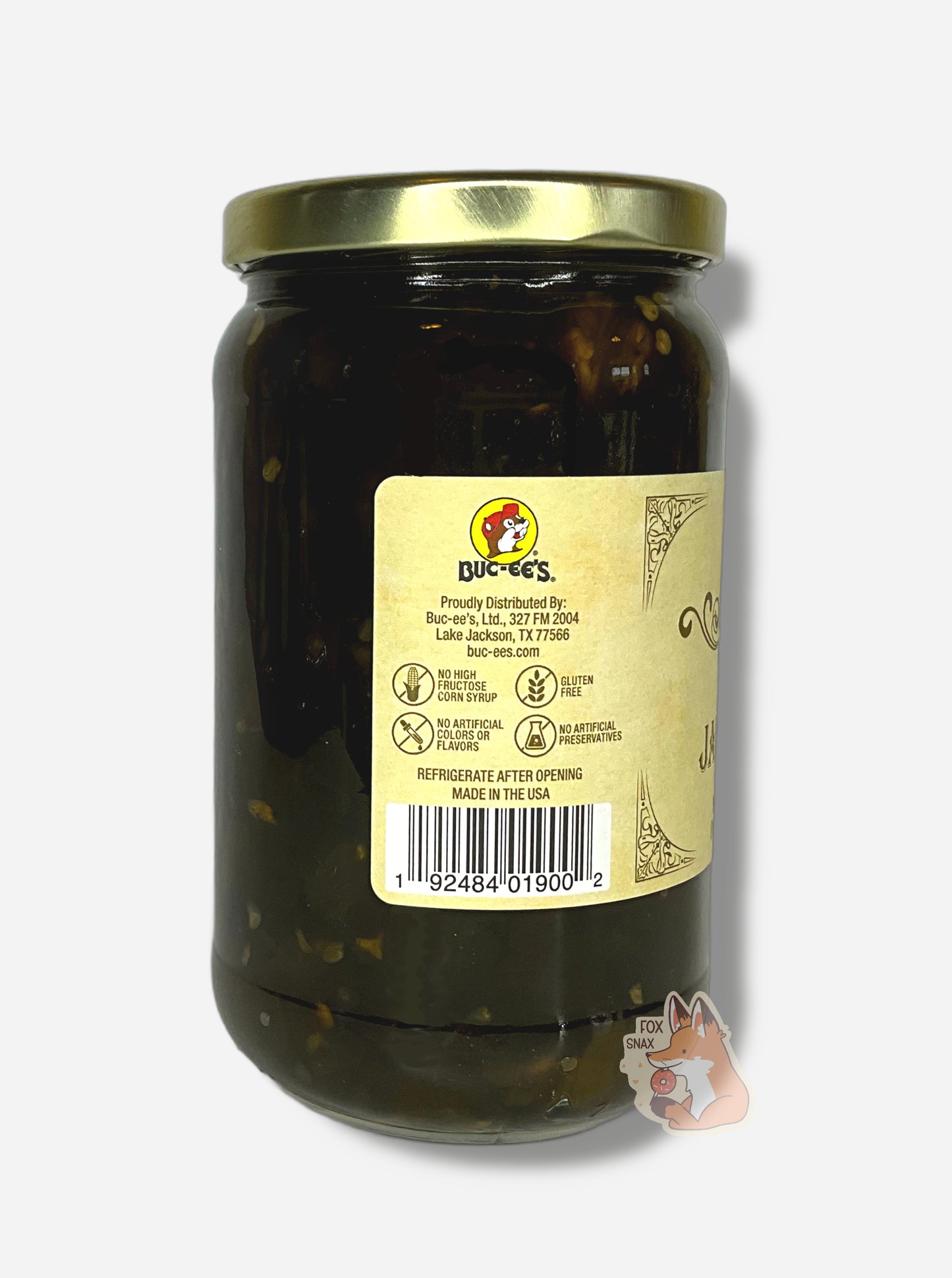 A picture of the left side of a glass jar of Buc-ee's Candied Jalapeños - the label is a "old-timey" sort of white/yellow with flared edges.  The middle reads No High Fructose Corn Syrup, No Artificial Colors Or Flavors, Gluten Free, No Artificial Preservatives. In the jar, dark green jalapeños can be seen.