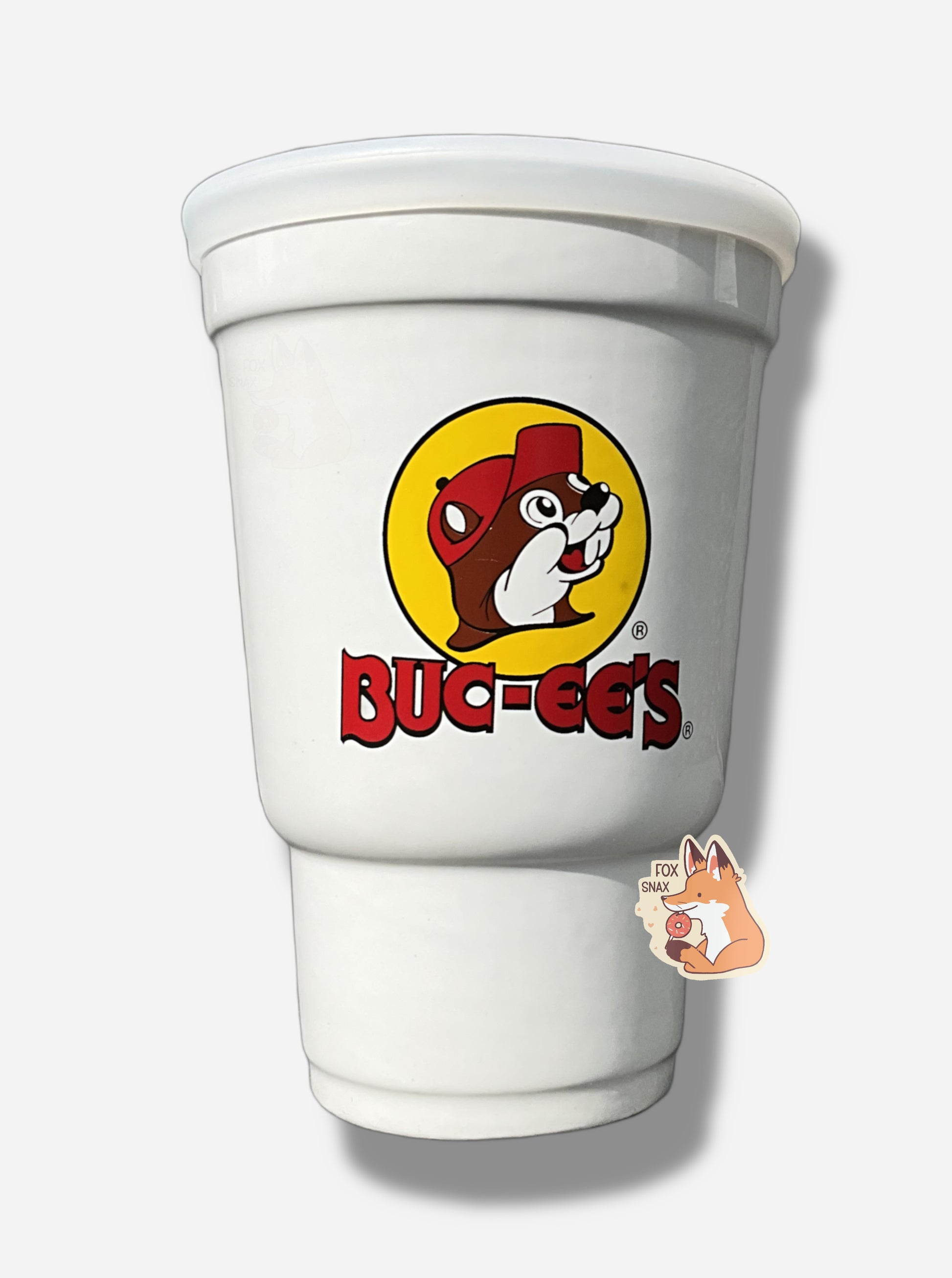 A picture of the back of a large white ceramic candle holder, made to look exactly like a Buc-ee's stryofoam drink cup.  The surface of the cup has the Buc-ee's logo: a cheerful brown-furred beaver with a massive overbite, wearing a ball cap, and underneath it in red text, BUC-EE'S.