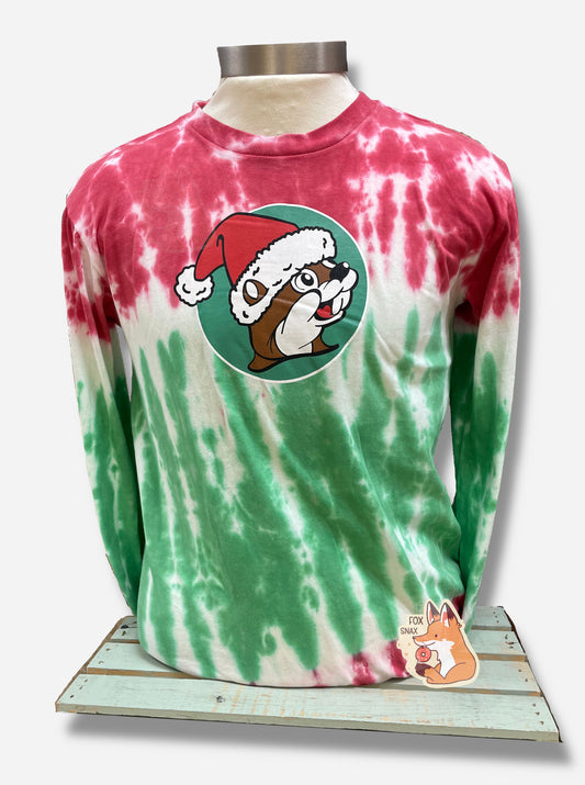 A picture of a red, white, and green Christmas tie-dye long sleeve shirt, resting on a manikin body.  The top of the shirt - sleeves, upper chest - is mostly red, with some white streaks.  A small band of uneven white is around the upper/middle chest, which fades down into green at the bottom around the belly.  In the middle is the Buc-ee's logo, but the background is green, and Buc-ee the Beaver is wearing a red Santa hat with a white pom on the end, instead of his usual ball cap.