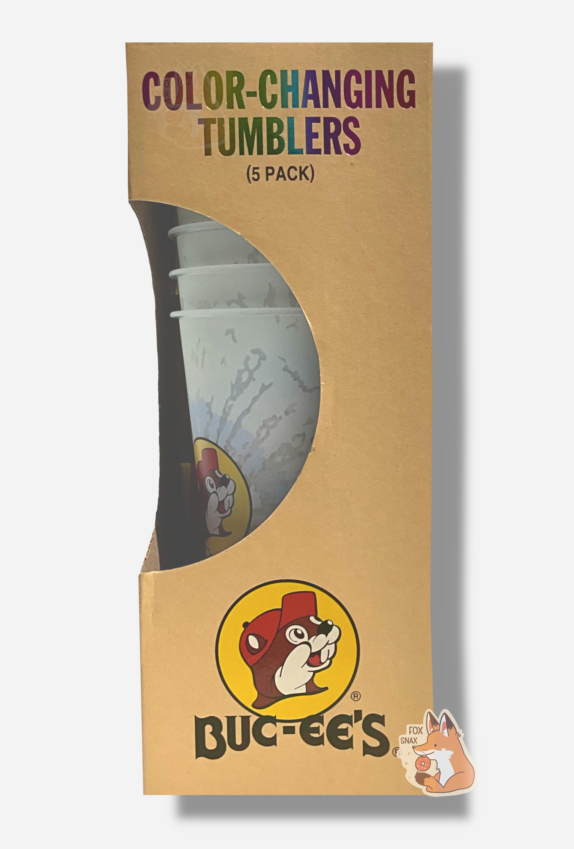 A picture of a tall, thin cardbox box.  The top of the box reads COLOR-CHANGING TUMBLERS.  In the middle is a semicircle cut out, which exposes the plastic tumblers.  Several tumblers can be seen, and they show a faded, white-ish plastic tumbler with a faint tie-dye pattern through the semicircle.  Each of the tumblers is tall, plastic, and has the Buc-ee's logo on it.