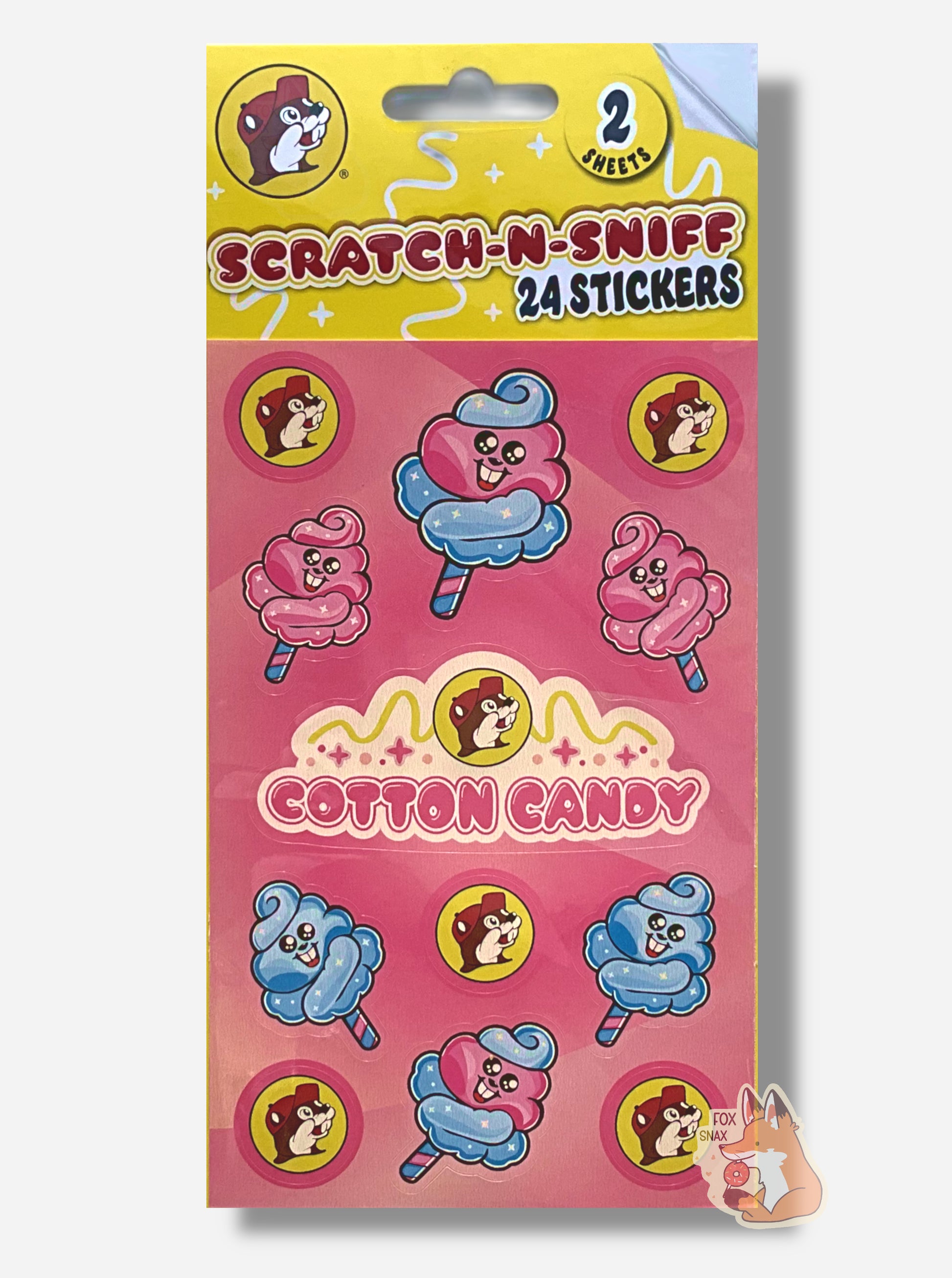 A rectangular package of Buc-ee's Scratch-N-Sniff Cotton Candy stickers.  The stickers on the package are the Buc-ee's logo - a brown-furred beaver with a massive overbite, pink cotton candy puffs with a beaver grin on its body, blue cotton candy puffs with a beaver grin on its body, a larger pink/blue puff with a beaver grin (it's all a bit surreal), and in the middle, a Buc-ee's logo with the words COTTON CANDY.  The top of the package reads 2 SHEETS, then SCRATCH-N-SNIFF, 24 STICKERS