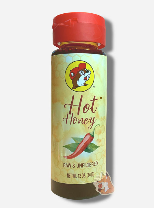 A plastic bottle of Buc-ee's Hot Honey.  The top of the bottle is a plastic red flip top.  The bottom is clear plastic; the brown/yellow honey inside can be seen.  A label surrounds the bottle, which reads HOT HONEY in brown cursive text, then RAW & UNFILTERED, then NET WT. 12 OZ (340G).  On the top of the label is the Buc-ee's logo: a cheerful brown-furred beaver wearing a red ball cap. The bottom shows a red hot pepper, framed by green leaves. 