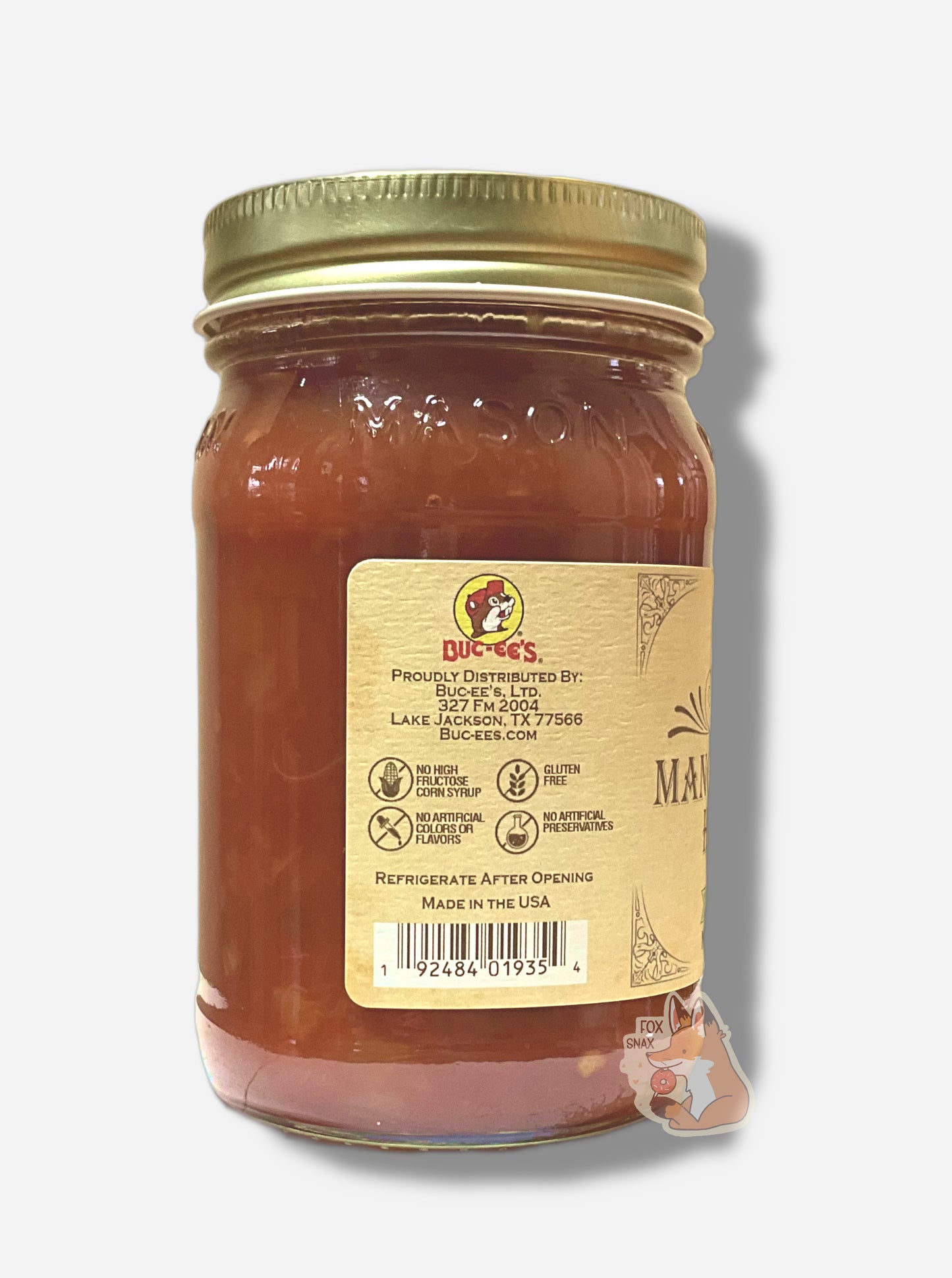 A picture of the left side of a glass jar of Buc-ee's Mango  Habanero Salsa - the label is a "old-timey" sort of white/yellow with flared edges.  The middle reads No High Fructose Corn Syrup, No Artificial Colors Or Flavors, Gluten Free, No Artificial Preservatives. In the jar, reddish salsa can be seen.