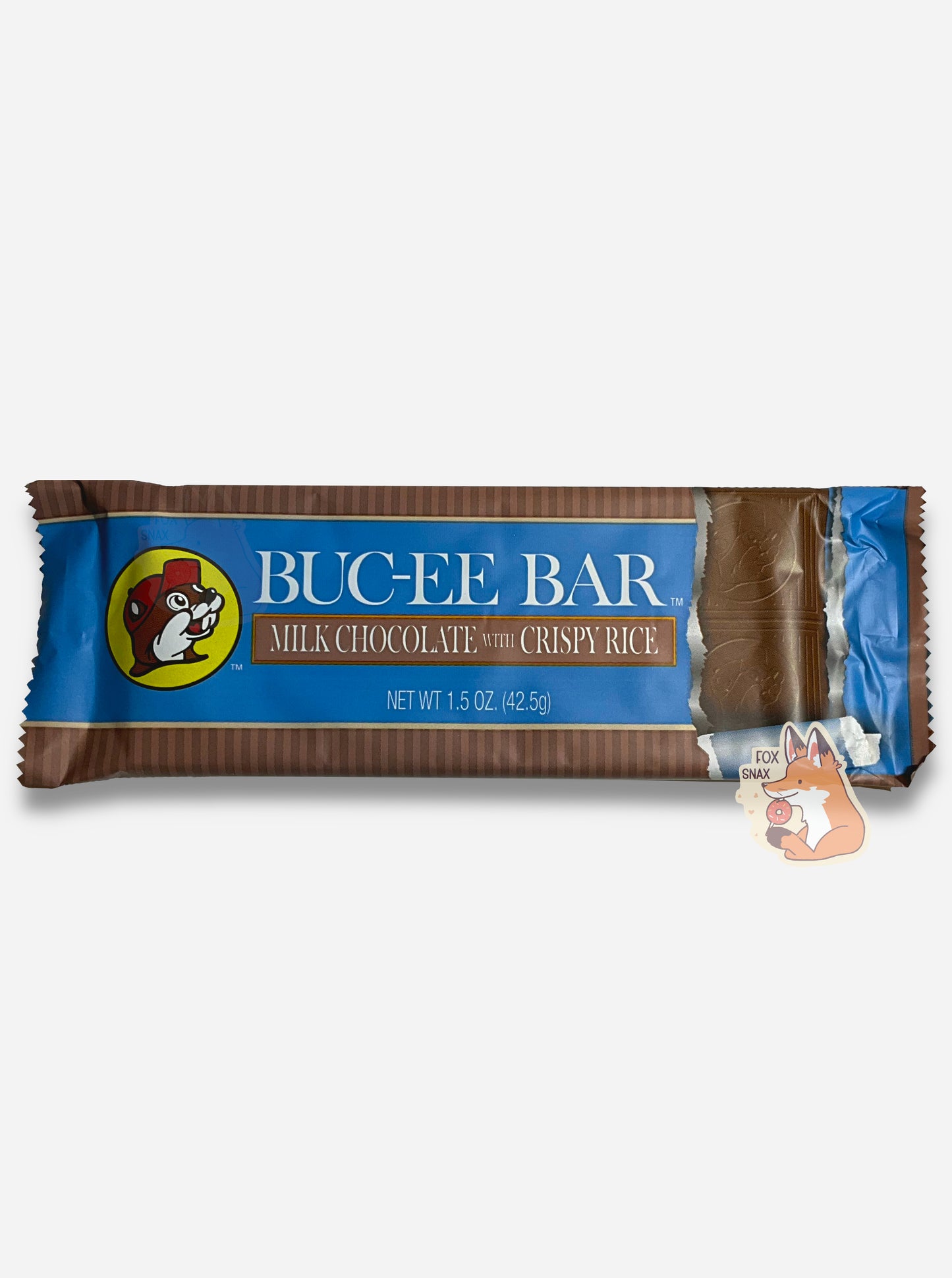 A picture of a rectangular bar of a Buc-ee Bar.  The package reads BUC-EE BAR, then MILK CHOCOLATE WITH CRISPY RICE.  The center part of the bar is a blue, with the Buc-ee The Beaver logo on the left.  On the right is a picture of the bar - it shows several squares with the Buc-ee's logo inset.