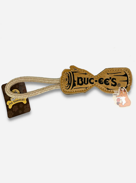 A picture of a Buc-ee's "Pet Essentials" Log Rope dog toy.  The body of the toy is shaped like a log - roughly - with a flat body and a dip in the middle, presumably to make it easier for a dog to bite it.  On one end is a strong tan rope.  The body of the tool is tan, and also has a black outline of a log with BUC-EE'S written in the middle.  Both ends of the  rope are tied into one end of the "log", making a loop for a person to hold on to.  A rectangular tag says BUC-EE'S PET ESSENTIALS.