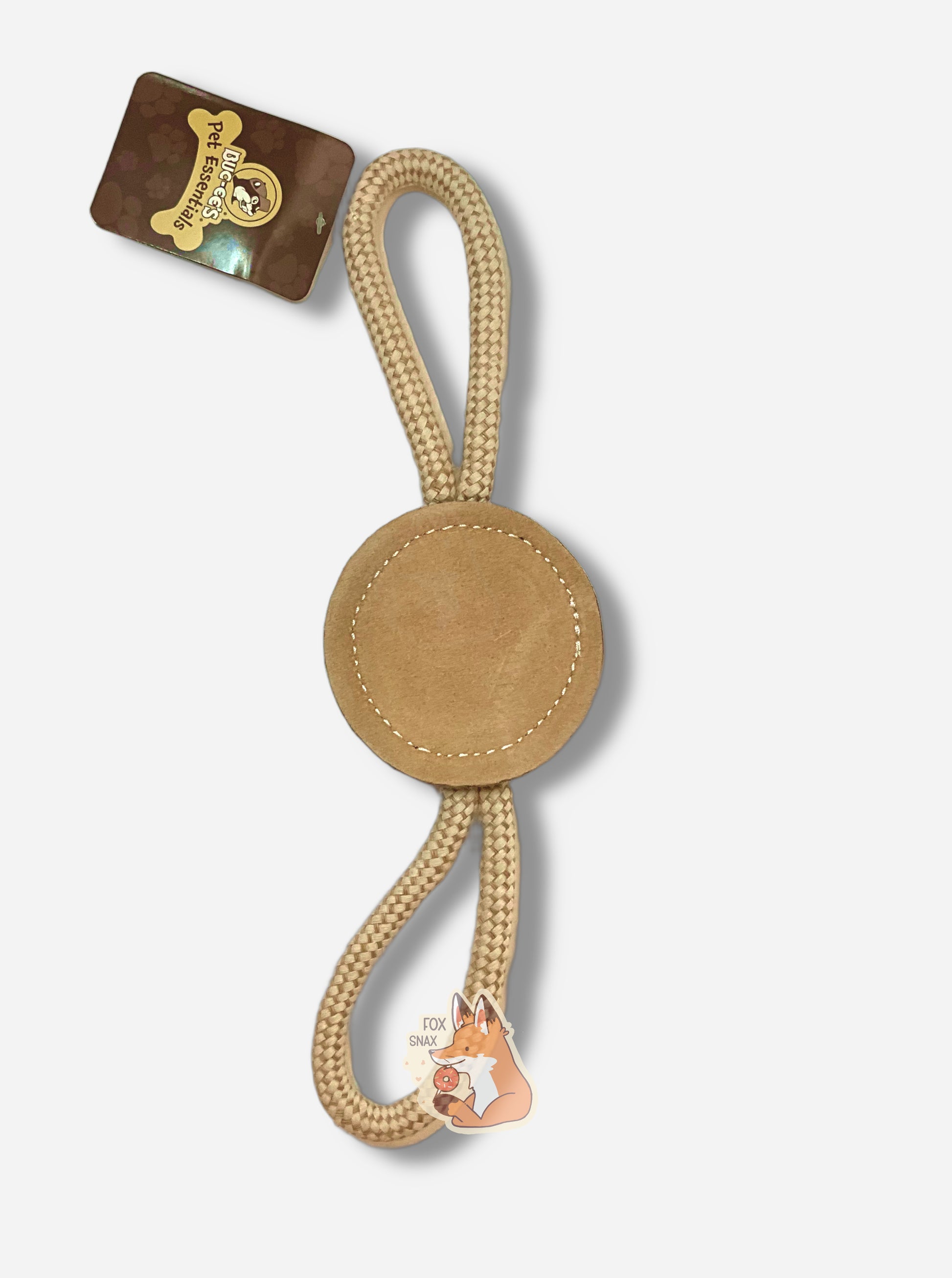 A picture of a Buc-ee's "Pet Essentials" Natural Disc dog toy.  The body of the toy is shaped like a circle - made of a material allowing a dog, if they so chose, to bite it.  On both ends are strong tan ropes that form a loop back to the body of the circle.  The body of the tool is tan, and also has a black outline of Buc-ee The Beaver.  The ends of the  rope are tied into one end of the "log", making a loop for a person (or dog) to hold on to.  A brown rectangular tag says BUC-EE'S PET ESSENTIALS.
