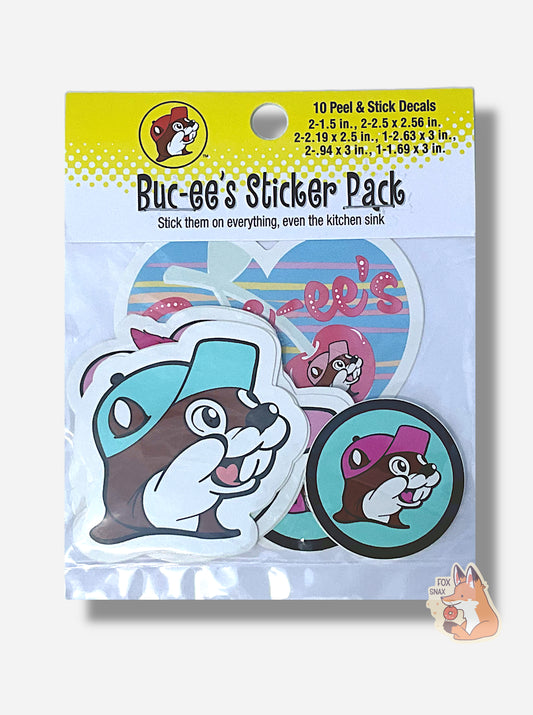 A picture of the front of Buc-ee's Pink And Blue And Drink Sticker Pack.  The cardboard label on the top of the bag indicates there are 10 peel & stick decals inside. The text on the label reads "BUC-EE'S STICKER PACK", then "Stick them on everything, even the kitchen sink".  Inside the bag, you can see a large Buc-ee's logo with a light blue cap, a smaller Buc-ee's logo with a pink cap and a blue background, and heart Buc-ee's logo, and several other half-obscured stickers.