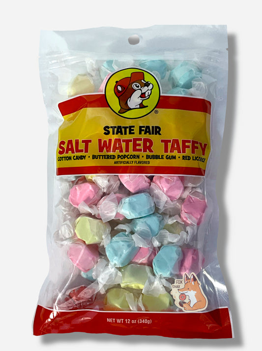 A picture of the front of a plastic bag of Buc-ee's State Fair Salt Water Taffy.  The bag is clear plastic with the Buc-ee's logo.  Inside it, twists of candy in four different wrapping colors (cotton candy, buttered popcorn, bubble gum, red licorice) can be seen.  The front of the bag has the Buc-ee's logo - a brown-furred beaver with a significant overbite, wearing a red ball cap - and reads:  STATE FAIR SALT WATER TAFFY, ARTIFICIALLY FLAVORED, then 12 OZ.