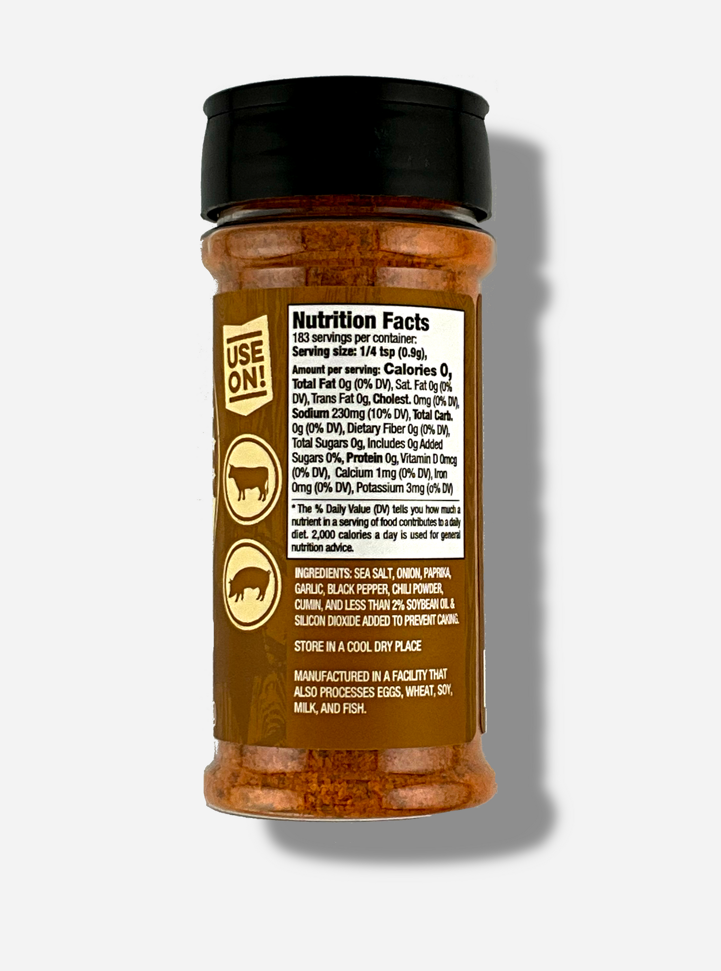 A picture of the back of a container of Texas Round Up Steak Seasoning. The container has a black plastic flip lid, and a clear plastic body.  The spices inside appear orange and grey. The tan label reads USE ON!, and beneath that, there is an outline of a cow and a pig.