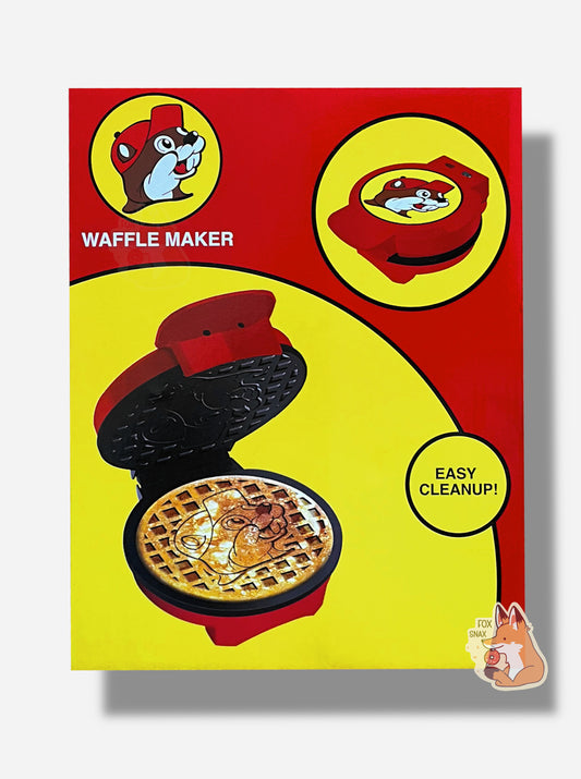 A picture of the front of a rectangular box containing one Buc-ee's Waffle Maker.  The box has the Buc-ee's logo in the top left, underneath which reads in a white font: WAFFLE MAKER.  The upper right has a picture of a red plastic circular waffle maker, with the Buc-ee's logo on the face.  The bottom left has a picture of the same waffle maker, with a golden brown waffle.  The waffle has the Buc-ee's logo in the middle, surrounded by a waffle grid pattern.  The bottom right reads: EASY CLEANUP!
