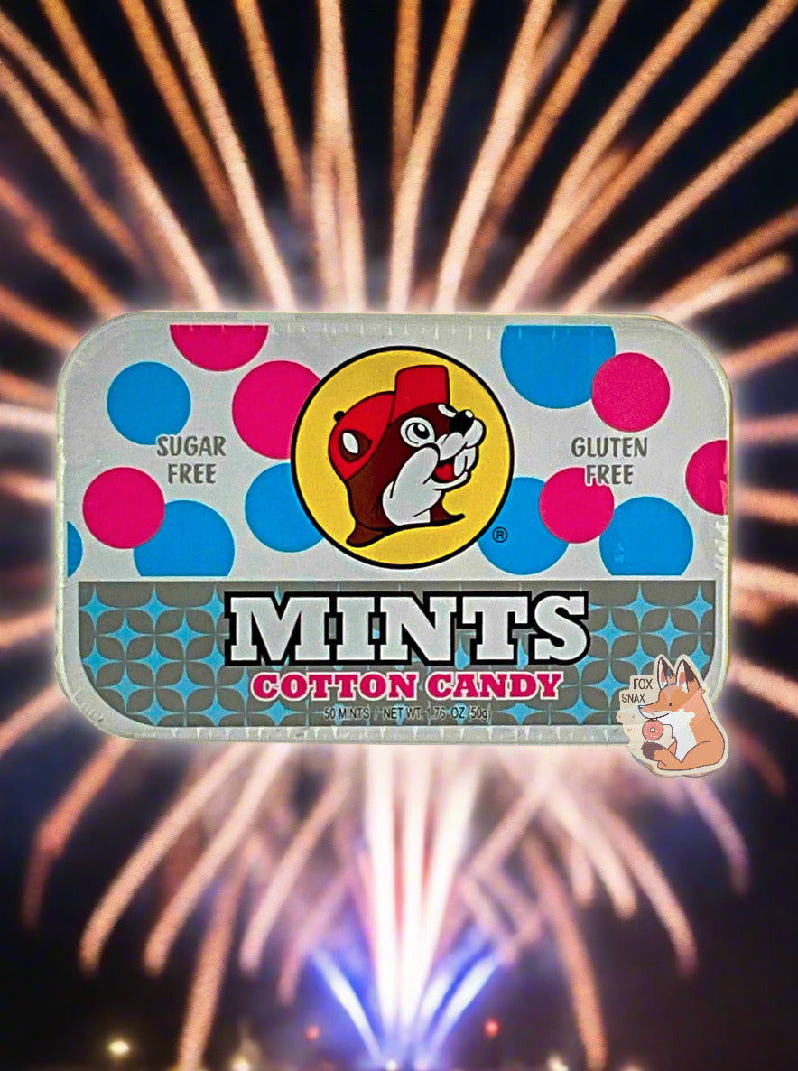 A picture of a tin of Buc-ees Cotton Candy Mints.  The cover is decorated with a big picture of Buc-ee The Beaver, and has pink and blue circles behind it to reflect the 'cotton candy' nature of the mints.  The tin reads Sugar Free, Gluten Free, Mints, Cotton Candy.  The background shows exploding orange and blue fireworks in a beautiful display.