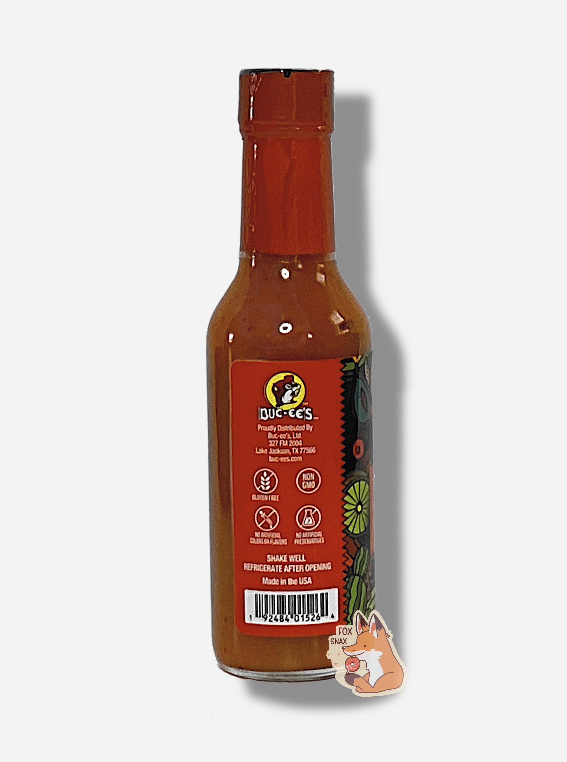 A picture of a small, tall glass bottle of hot sauce. The top of the bottle is sealed with a shiny orange plastic top.  The back reads GLUTEN FREE, NON GMO, NO ARTIFICIAL COLORS OR FLAVORS, NO ARTIFICIAL PRESERVATIVES, then SHAKE WELL and REFRIGERATE AFTER OPENING.  Made in the USA.  The sauce inside is red/orange.