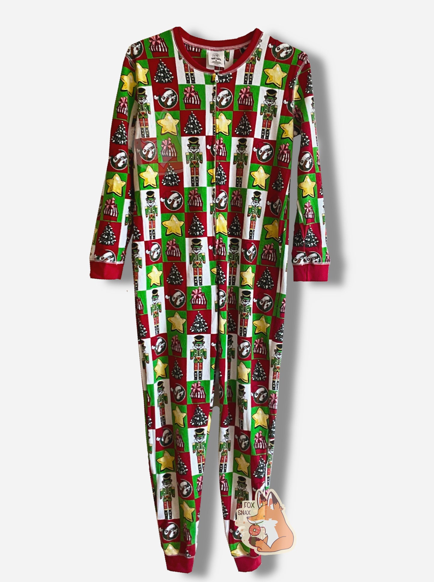 A picture of a large onesie that resembles Christmas wrapping.  Most of the wrapping is separated into squares or rectangles. The shapes have within them, alternately: yellow stars, Christmas trees, red wrapped presents with a pink bow, Buc-ee the Beaver dressed as a nutcracker with a green outfit.  The neck, sleeves, and ankles are in red.