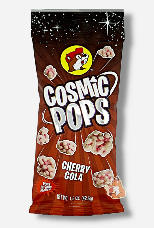 A picture of Buc-ee's Cosmic Pops, in Cherry Cola flavor.  The bag starts with stars against a black background at the top, then shows rays of alternating red colors poking out of the center, to give the impression that the pops - lumpy odd shaped candies - are emerging from the center.  A logo on the bottom reads POPS IN YOUR MOUTH!