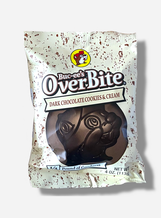 A picture of a package of a dark chocolate cookies & cream Buc-ee's OverBite.  The package is metallic and white, with brown flecks, and features a large picture of the candy, which is shaped like the Buc-ee's beaver mascot logo.  The package reads BUC-EE's OVERBITE, then DARK CHOCOLATE COOKIES & CREAM, then 1/4 POUND OF GOODNESS.