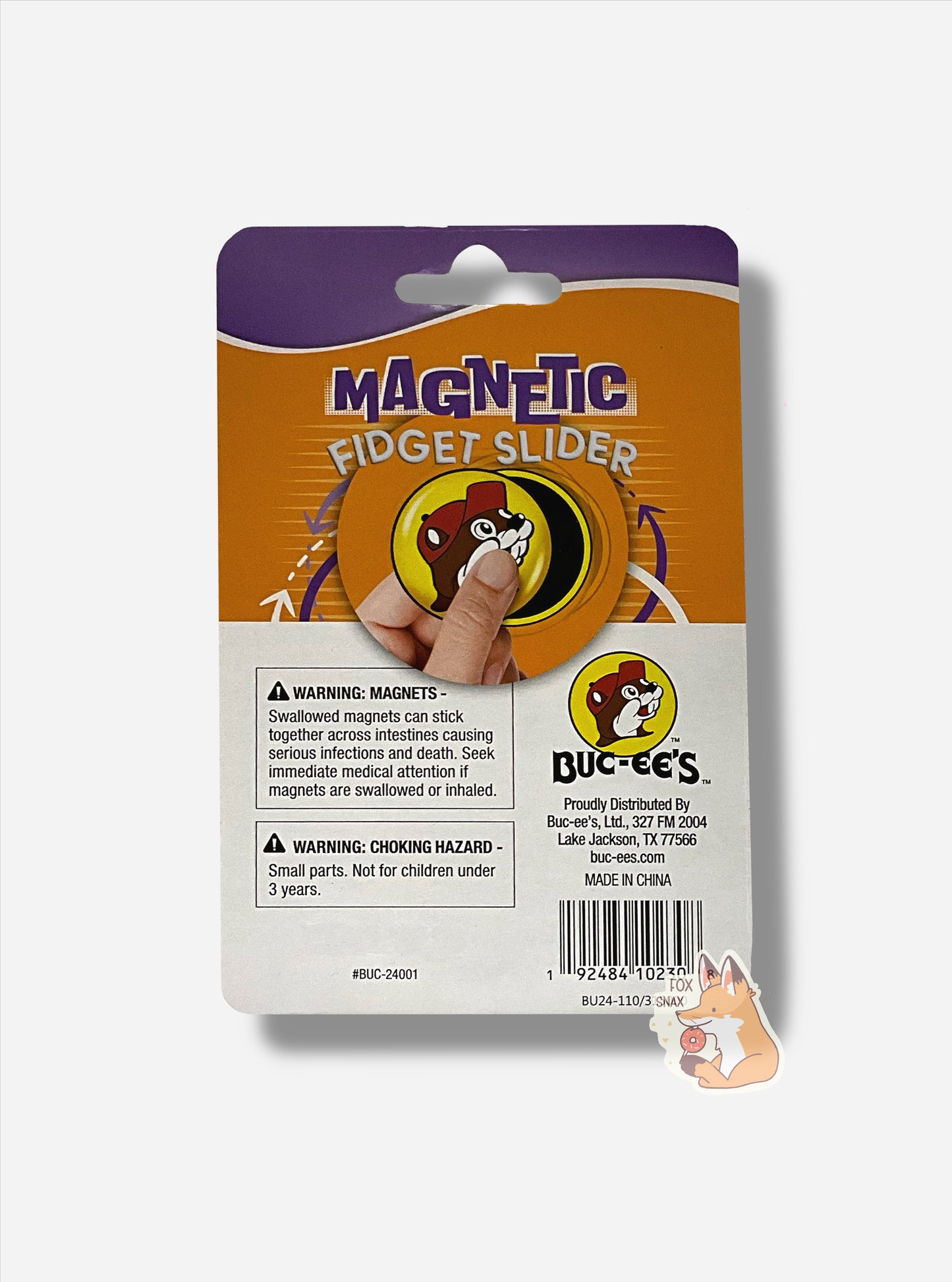 A picture of a rectangular package of Buc-ee's Magnetic Fidget Sliders.  The package is in purple at the top, then orange in the middle, then white at the bottom.  A warning reads WARNING- MAGNETS - SWALLOWED MAGNETS CAN STICK TOGETHER ACROSS INTESTINES CAUSING SERIOUS INFECTIONS AND DEATH. SEEK IMMEDIATE MEDICAL ATTENTION IF MAGNETS ARE SWALLOWED OR INHALED.  A second warning reads WARNING: CHOKING HAZARD.  SMALL PARTS. NOT FOR CHILDREN UNDER 3 YEARS.