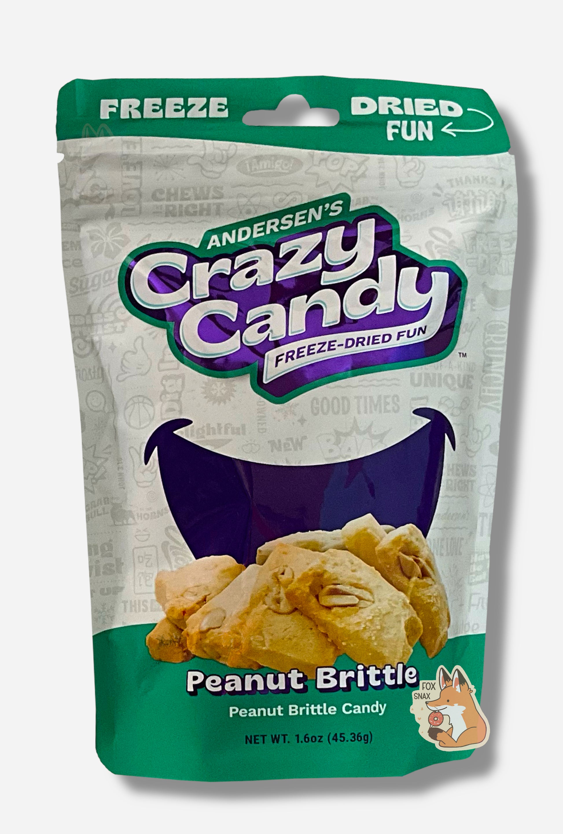 A large bag of Andersen's Peanut Brittle.  The front of the bag also says Peanut Brittle Candy, Net Weight 1.6 oz.  It's Fun, Happy, Candy.  The top and bottom of the bag are green, and the background is a large purple smile against a white background.