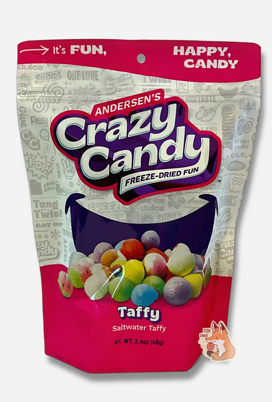 A large bag of Andersen's Taffy.  The front of the bag also says Saltwater Taffy, Net Weight 2.4 oz.  It's Fun, Happy, Candy.  The top and bottom of the bag are reddish pink, and the background is a large purple smile against a white background.