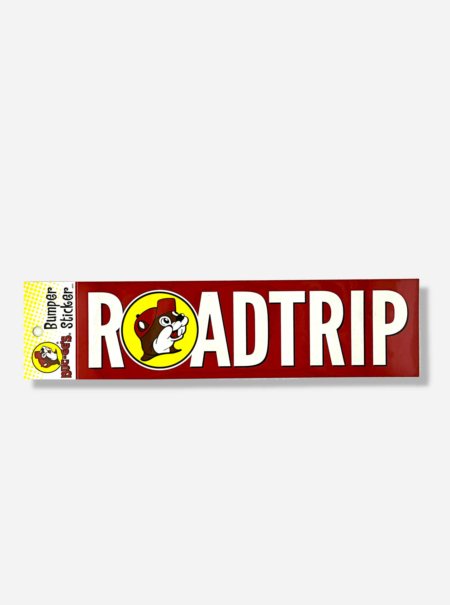 A picture of a red bumper sticker that says ROADTRIP.  The O in the word is replaced instead with the circular Buc-ee's logo.  The background is a solid red, and the letters are white, with the exception of the O, which is in yellow.