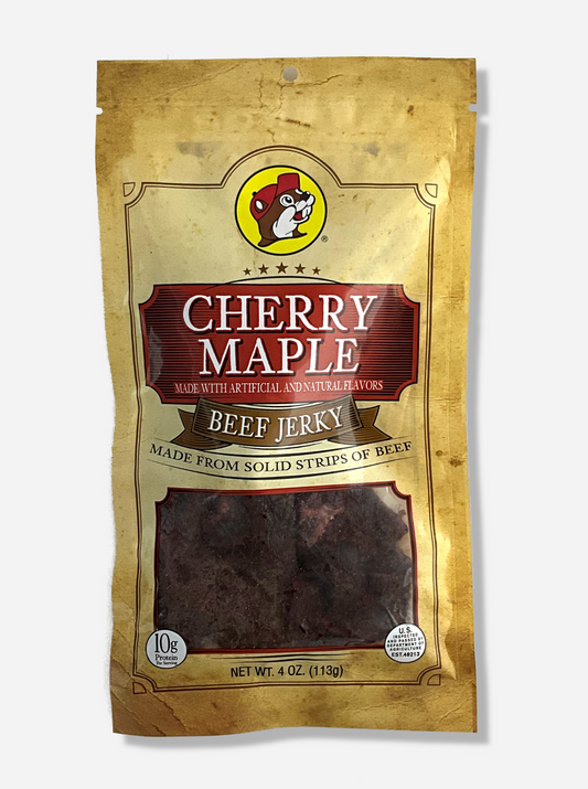 A picture of the front of a tan plastic bag of Buc-ee's Cherry Maple Beef Jerky.  The logo is in dark red with white text.The label underneath reads 'Made From Solid Strips Of Beef'.A small window on the bottom of the bag shows the dark brown/red dried jerky inside.  The bag has a picture of Buc-ee the Beaver on it.