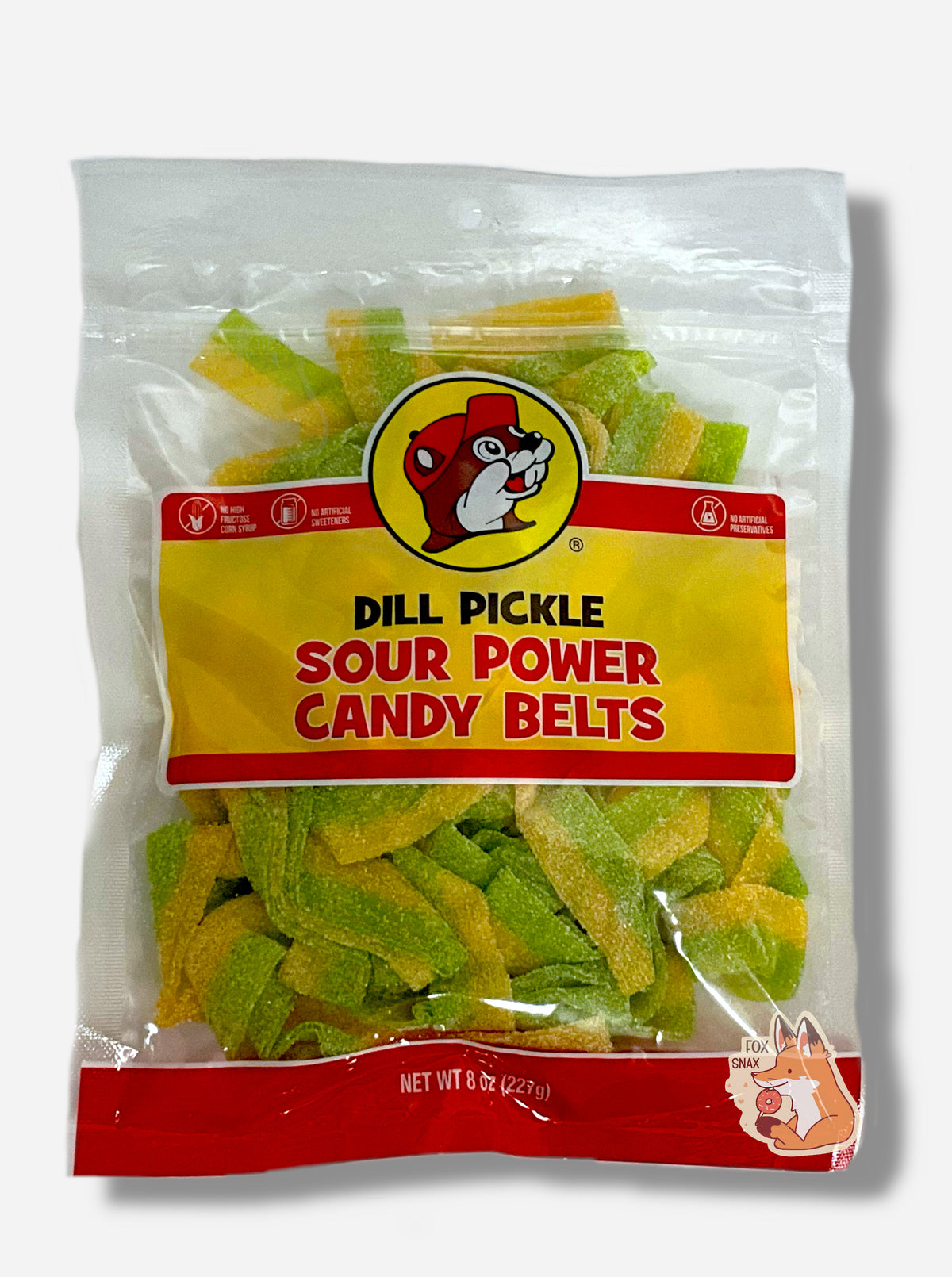 A clear square plastic bag of Buc-ee's Dill Pickle Sour Power Candy Belts.  Inside the bag are rectangular strips of candy, each about an inch and a half long.  The strips are green and yellow, and are covered in white sugar.  The bag reads "DILL PICKLE SOUR POWER CANDY BELTS, ARTIFICIALLY FLAVORED, Net Wt 8 Oz".  The Buc-ee's logo is front and center on the bag.  In the upper left are small circular logos reading "NO HIGH FRUCTOSE CORN SYRUP",  "NO ARTIFICIAL SWEETENERS", and "NO ARTIFICIAL PRESERVATIVES".