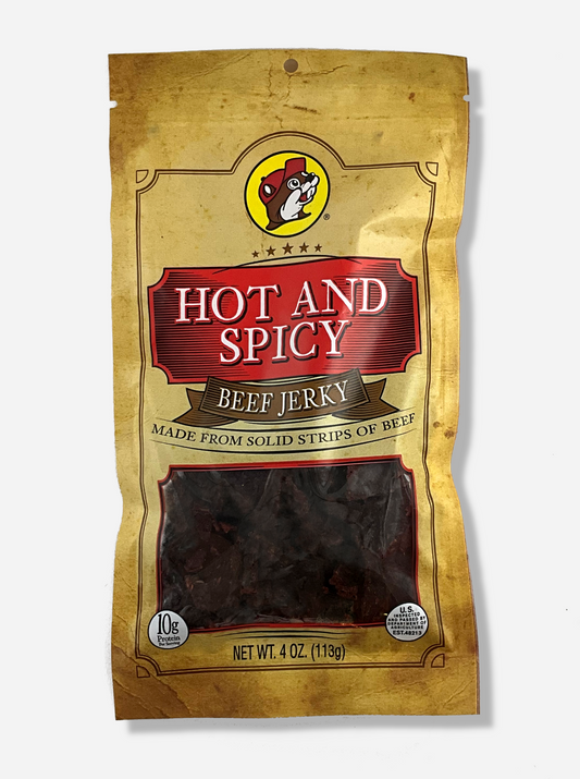 A picture of the front of a tan plastic bag of Buc-ee's Hot And Spicy Beef Jerky.  The logo is in bright red with white text.The label underneath reads 'Made From Solid Strips Of Beef'.A small window on the bottom of the bag shows the dark brown/red dried jerky inside.  The bag has a picture of Buc-ee the Beaver on it.