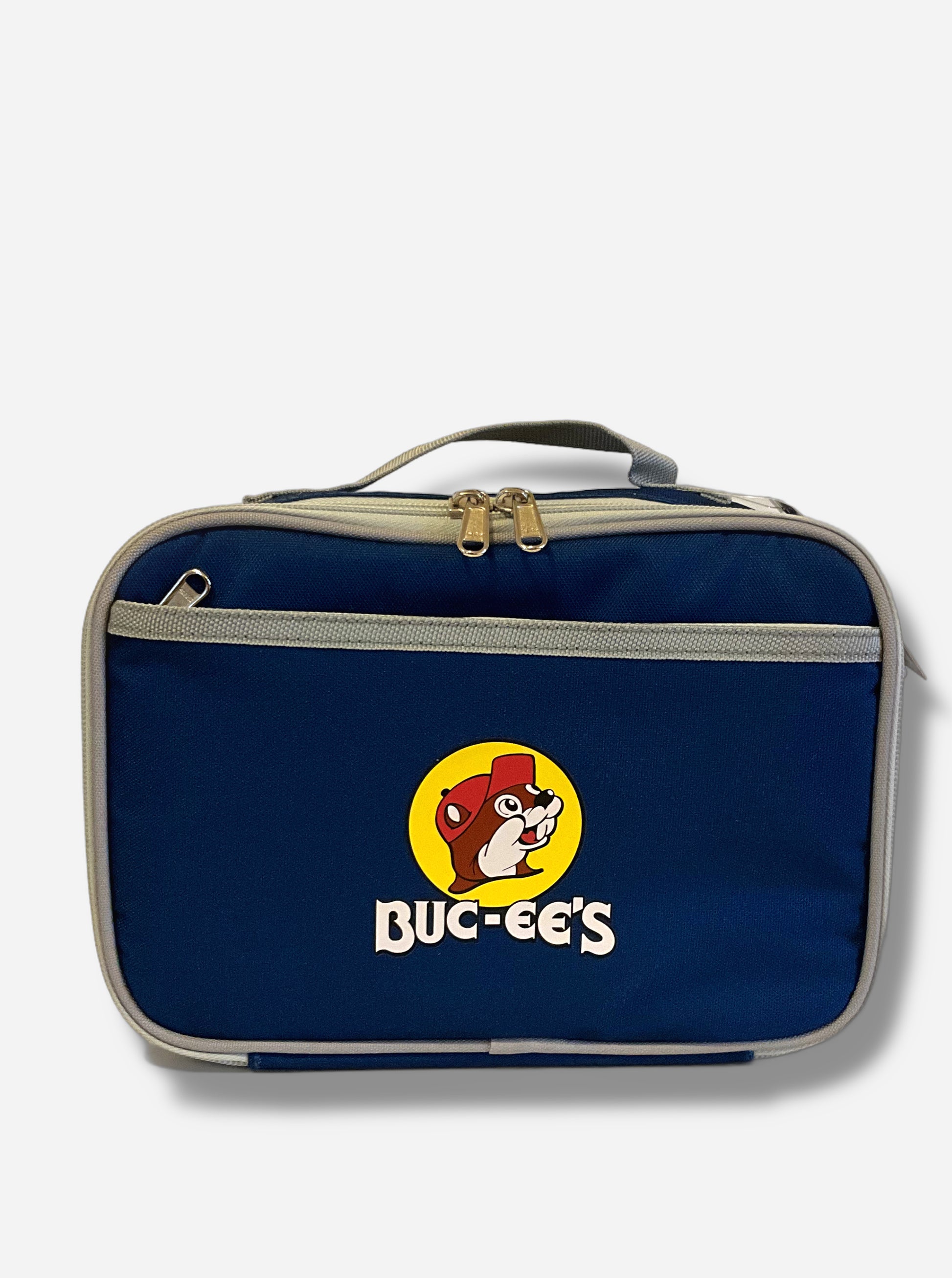 A picture of a front view of a children's lunch box.  The outer surface is made of blue polyester, and has a small tan strap on the top.  The front of the cooler has a picture of the Buc-ee's logo on it: a grinning beaver wearing a red hat against the background of a yellow circle.  Underneath the logo reads BUC-EE'S in white text. The front of the lunch box has a small zip pocket.  