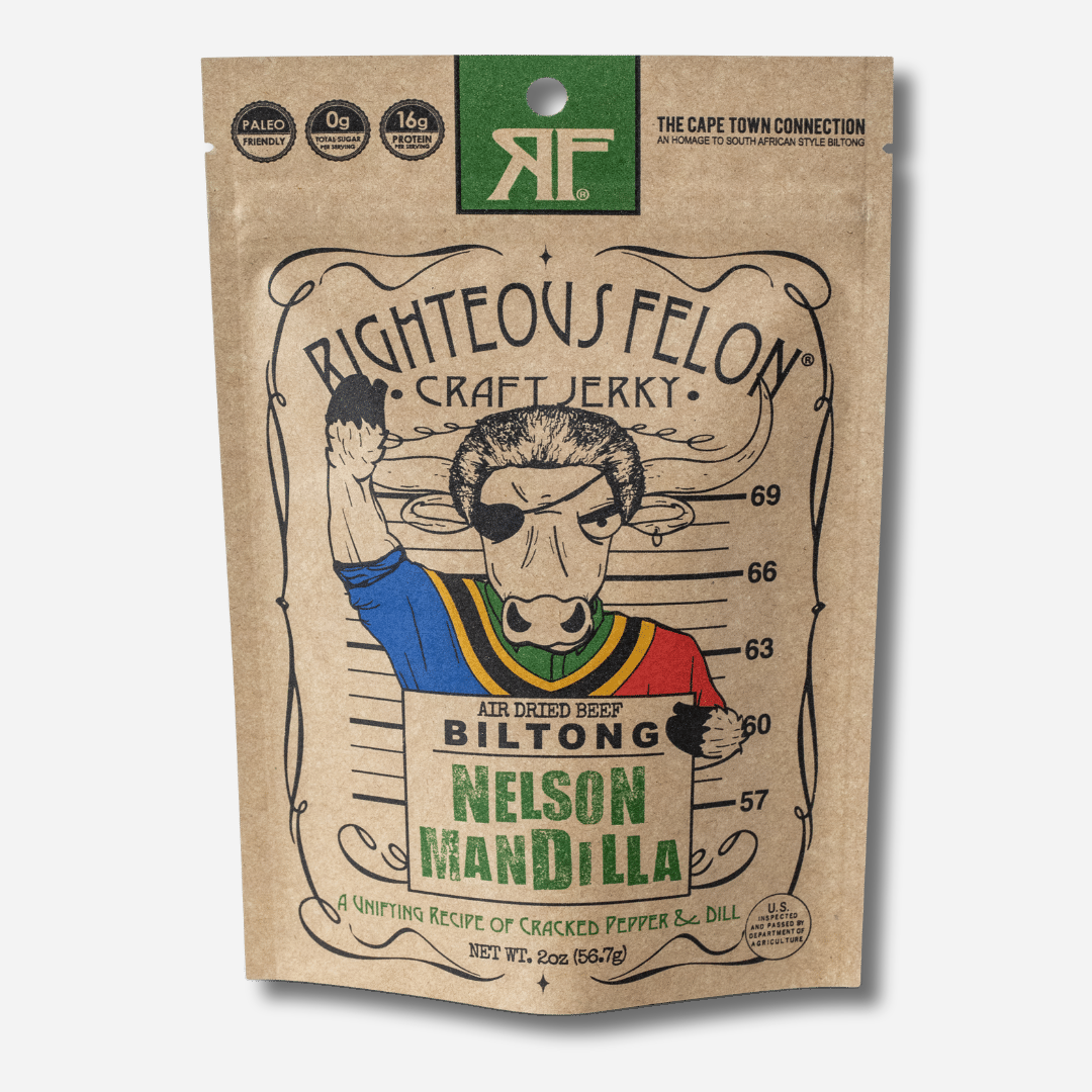 A picture of the front of a kraft paper bag of Righteous Felon Nelson ManDilla Biltong with a green RF logo and Paleo Friendly, 0g Total Sugar, and 16g Protein per Serving badges.  A cartoon bull in a colorful South African style shirt raises a fist while holding a mugshot sign that reads "Air Dried Beef Biltong, Nelson ManDilla".  At the bottom: "A Unifying Recipe of Cracked Pepper & Dill", Net Wt. 2oz.