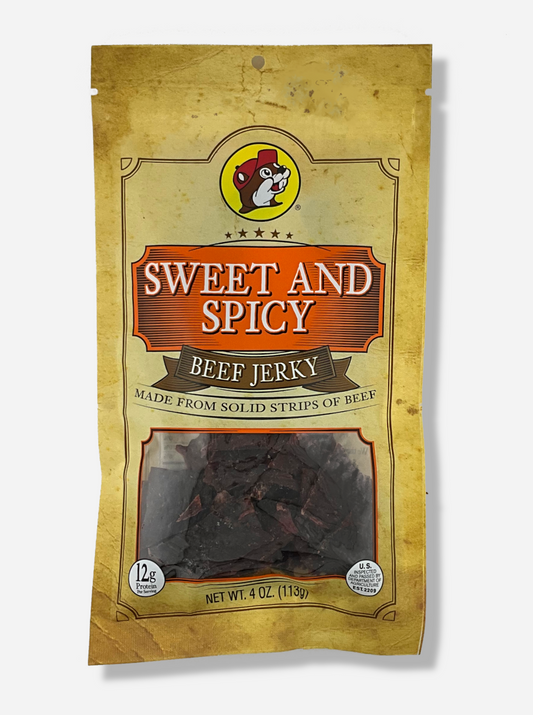 A picture of the front of a tan plastic bag of Buc-ee's Sweet And Spicy Beef Jerky.  The logo is in orange with white text.  The label underneath reads 'Made From Solid Strips Of Beef'.A small window on the bottom of the bag shows the dark brown/red dried jerky inside.  The bag has a picture of Buc-ee the Beaver on it.