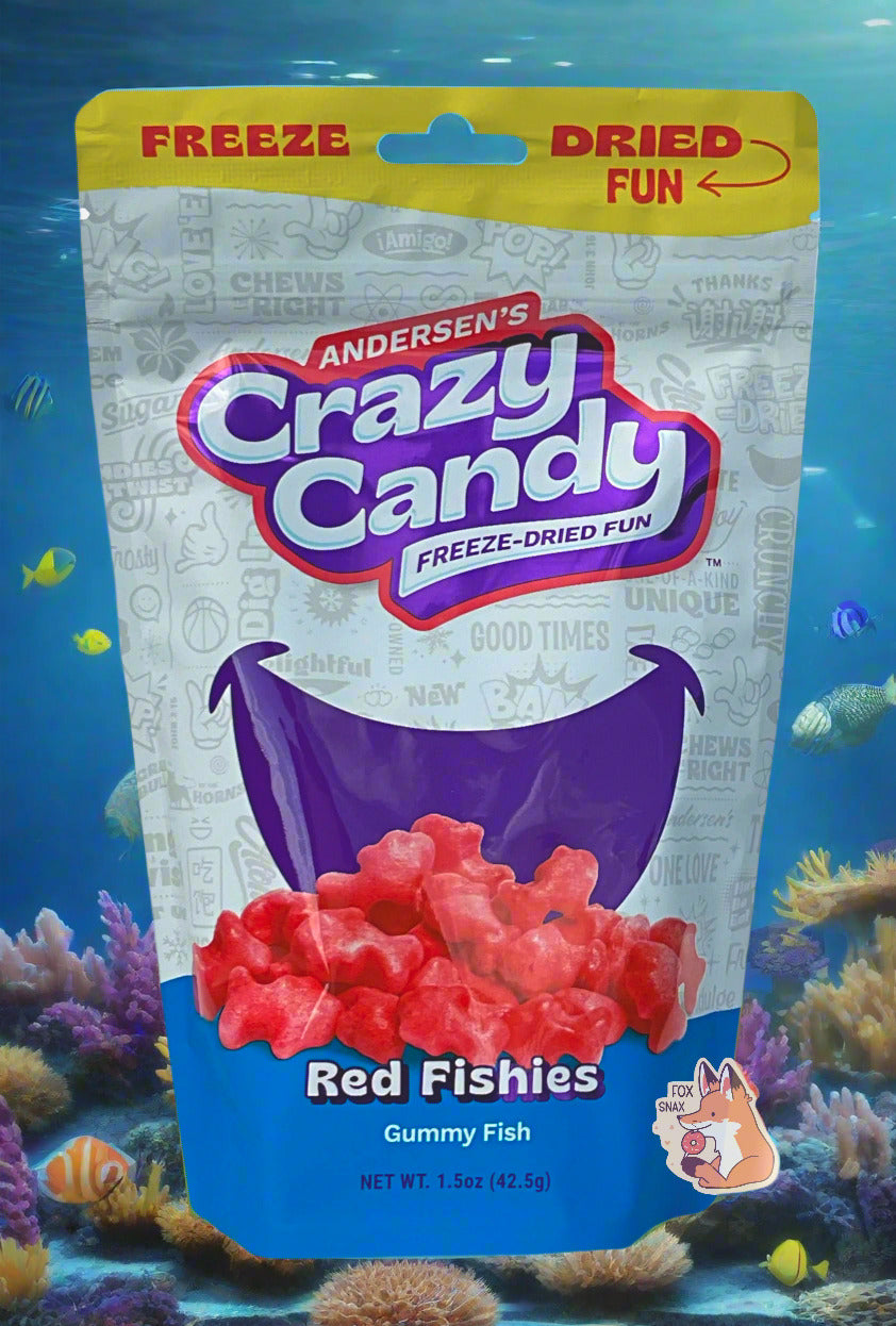 A large bag of Andersen's Red Fishies  The front of the bag also says Gummy Fish, Net Weight 1.5 oz.  The top of the bag is yellow, and in red text says "FREEZE DRIED FUN".  The middle bottom of the bag shows a large series of puffy, red candy fish,  and the background is a large dark blue smile against a white background with text.  The background is an underwater tropical ocean view, covered in beautiful tropical fish.