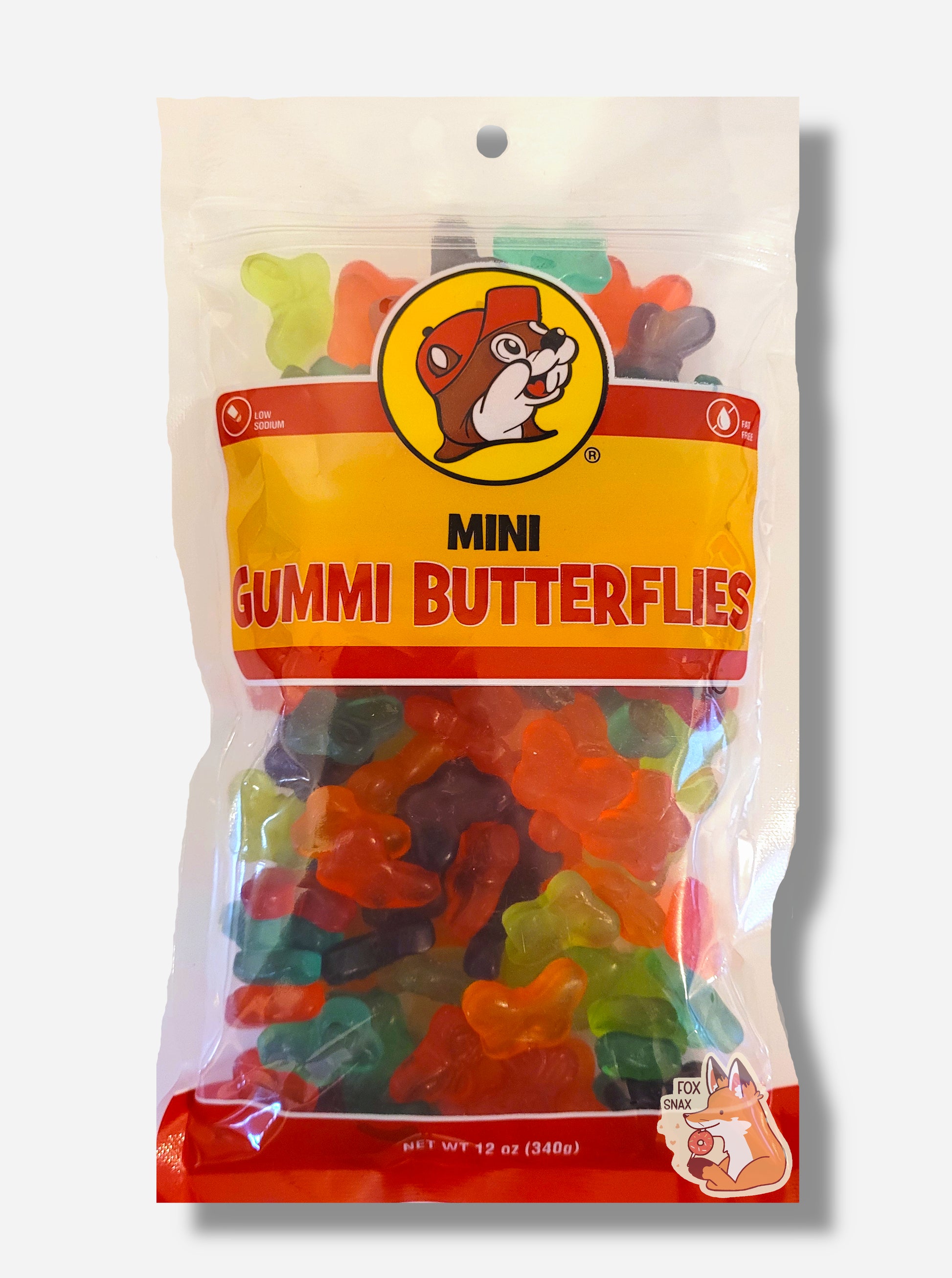 A picture of the front of a resealable bag of Buc-ee's Mini Gummi Butterflies, which are brightly colored gummi butterflies in different flavors.  The bag reads MINI GUMMI BUTTERFLIES, Low Sodium, Fat Free, and has a picture of Buc-ee the Beaver on it. The butterflies inside are buttlerfly-shaped, and are multiple shades of red, orange, green, blue, and purple.