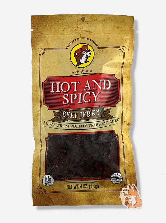 A picture of the front of a tan plastic bag of Buc-ee's Hot And Spicy Beef Jerky.  The logo is in bright red with white text.The label underneath reads 'Made From Solid Strips Of Beef'.A small window on the bottom of the bag shows the dark brown/red dried jerky inside.  The bag has a picture of Buc-ee the Beaver on it.